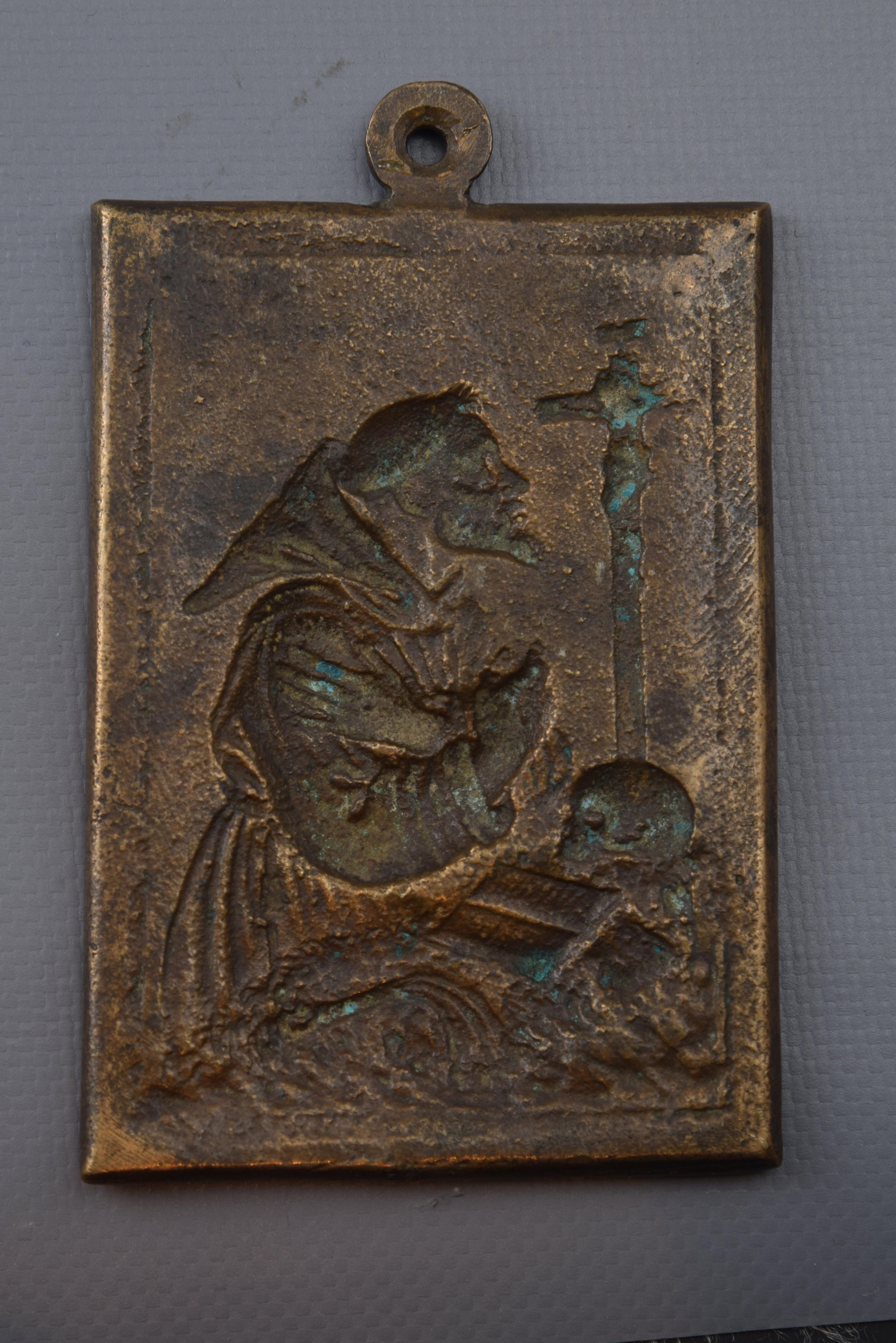 Devotional plaque, San Francisco de Asis, bronze, 17th century.
Devotional plate made of rectangular bronze that has a ring at the top and a simple frame to highlight the relief of its front. The Saint, dressed in Franciscan habit and cord, crosses
