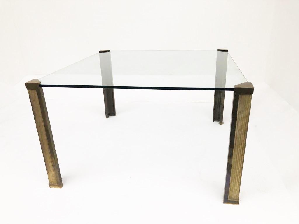 Impressive square glass dining table with cast bronze legs designed by Peter Ghyczy.

The thick glass top is supported in the corners by the heavy bronze legs so it looks to be floating.

Beautiful patina on the legs

Thick 15mm clear glass