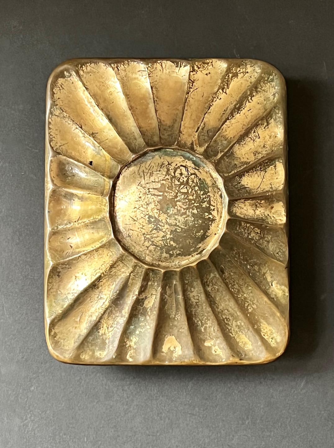 A heavy bronze push or pull door handle with raised sunburst design, mid-late 20th century, European.

A hand-made piece with lots of patina. The metal has a golden finish, with signs of wear revealing darker tones below (also see picture of the