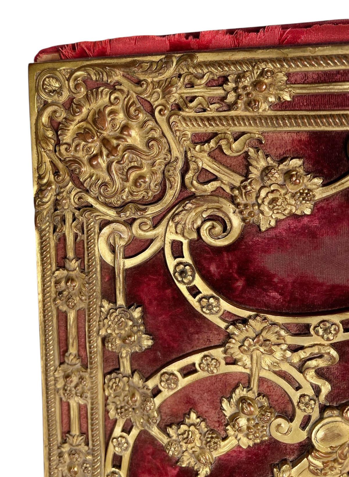 Questo squisito portafoglio in bronzo dorato, attribuito al rinomato E.F. A. Caldwell & Co. di New York, è un lussuoso esempio di artigianato dei primi del Novecento. Caratterizzato da dettagli dorati in bronzo, il pezzo è ornato da intricate facce