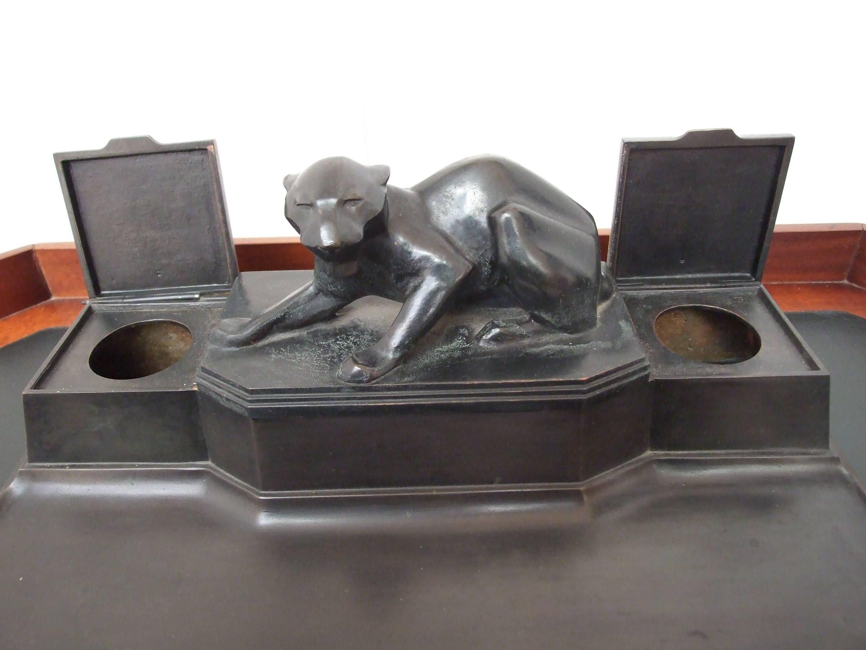 A bronze double inkwell with integral pen tray surmounted by a sculpture of a tiger, signed by A Puchegger circa 1910, measure: 14cm (5.5in) high, 34.25cm (13.5in) wide, 18cm (7in) deep. Anton Puchegger, Austrian School, born at Payerbach, circa