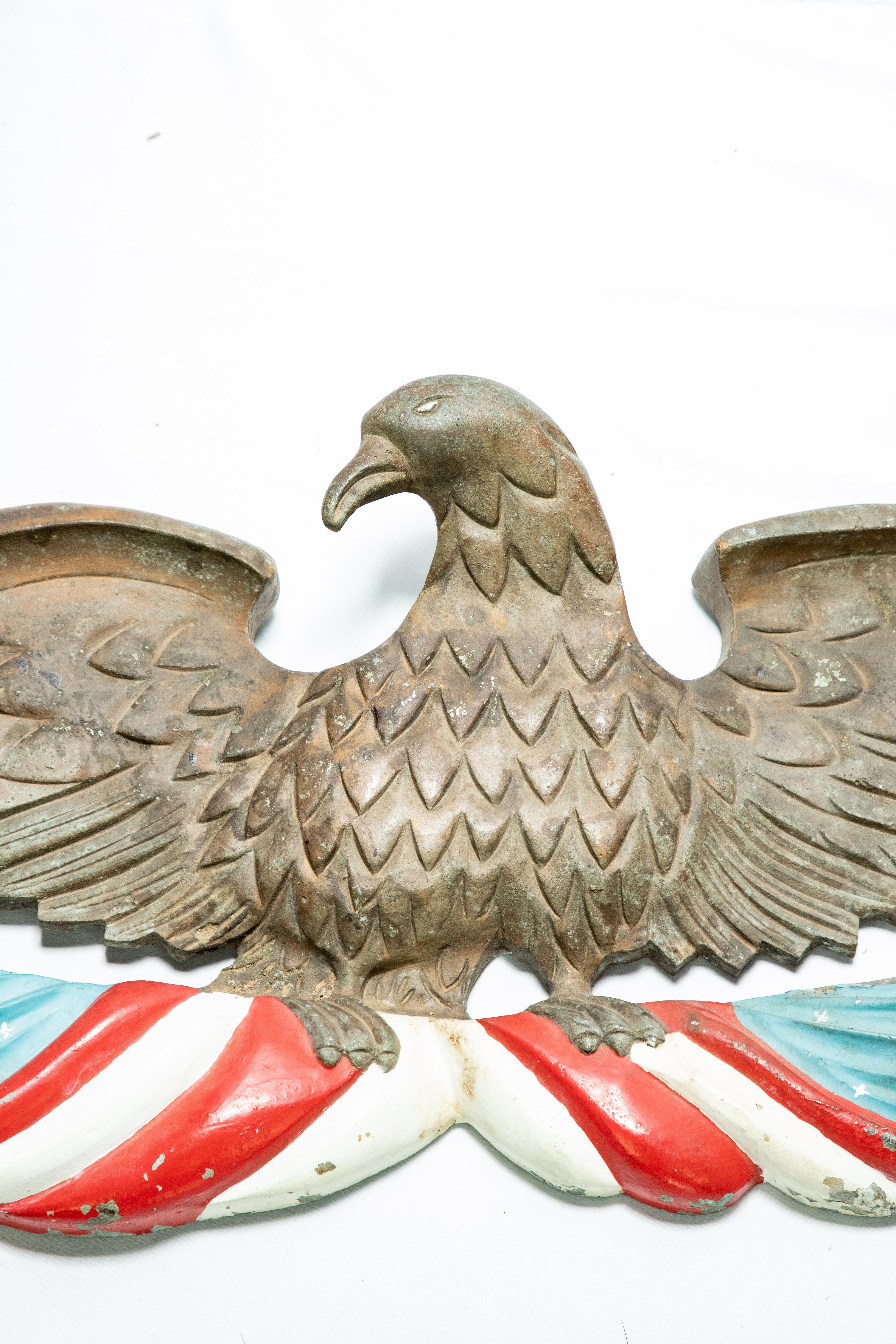 Offering this stunning cast bronze Eagle wall plaque. This eagle spreads its wings and holding in its talons is a red white and blue themed fabric.