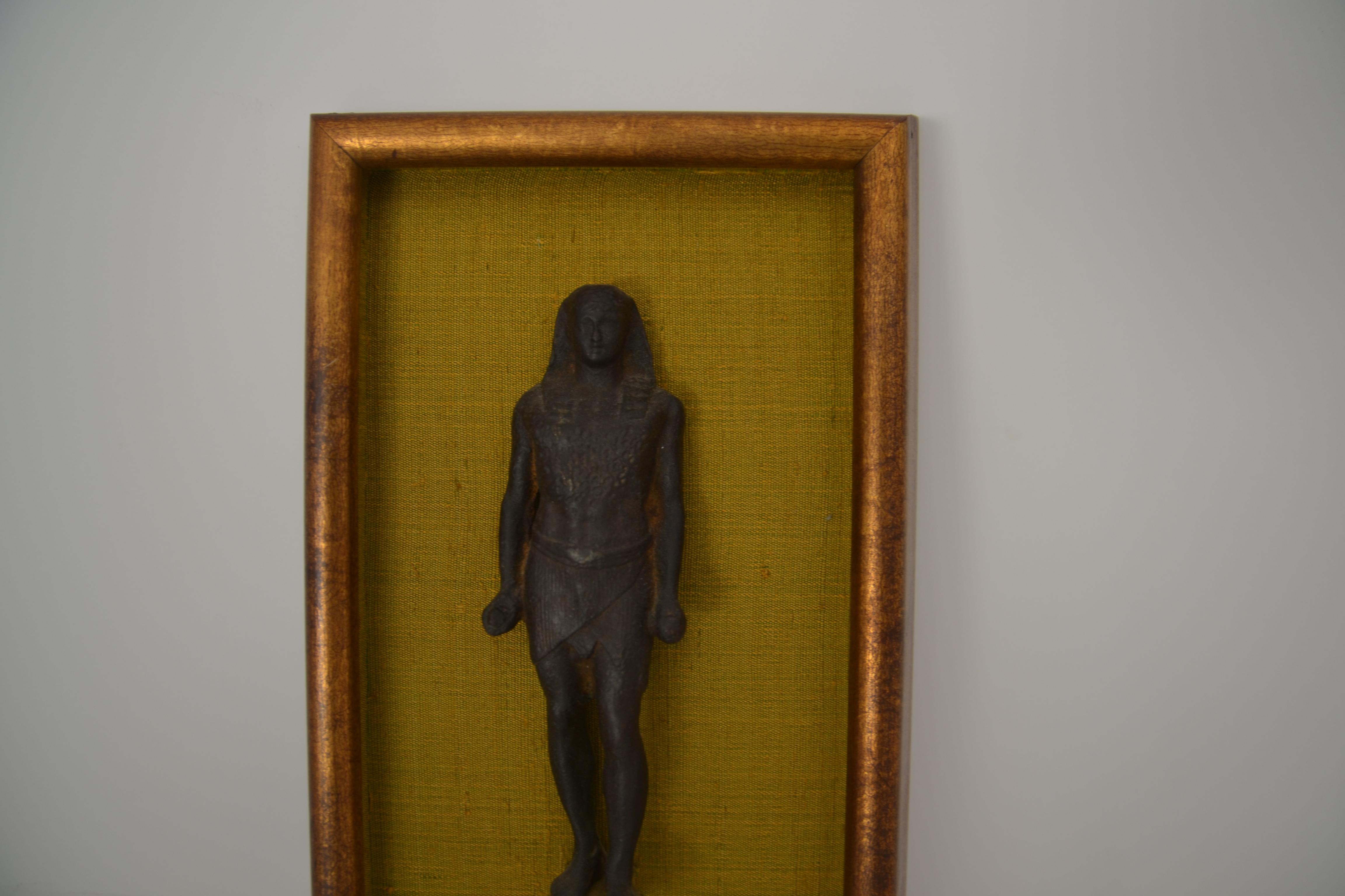 Egyptian bronze statue in a wood frame.