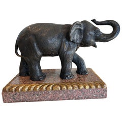 Bronze elephant by Theodore Alexander on rococo style rose granite base