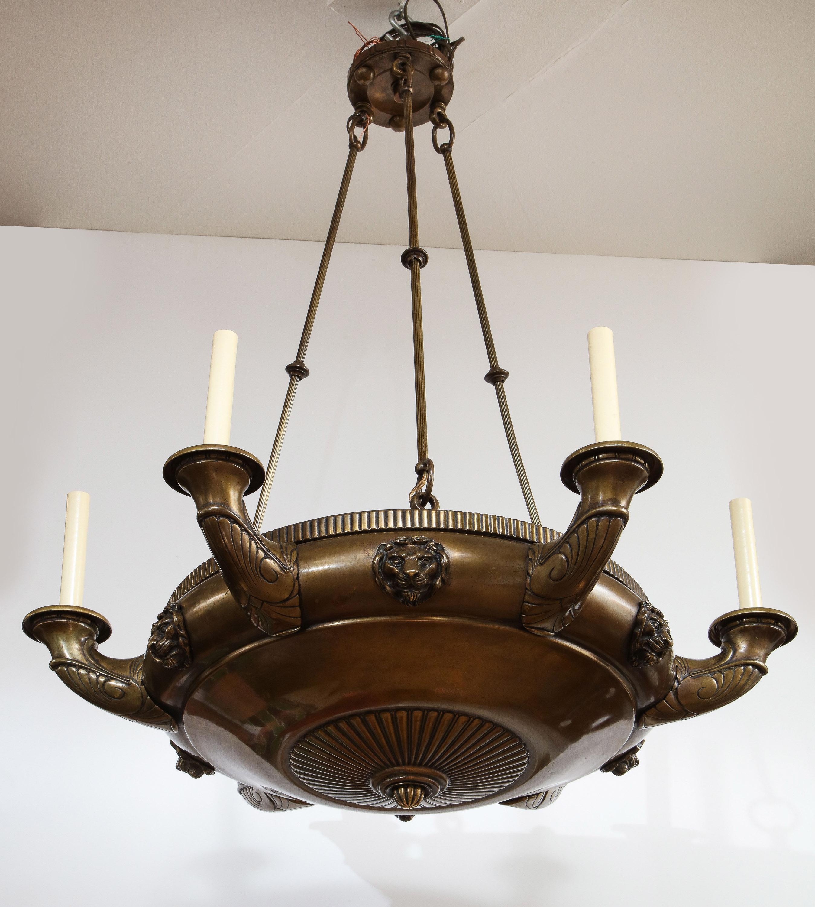 Fine 19th century bronze Empire style six light chandelier, now electrified, having lion mask mounts, palmette decorated arms and ribbed basin, suspended from three bronze rods with ring turned collars, the whole with rich patina.