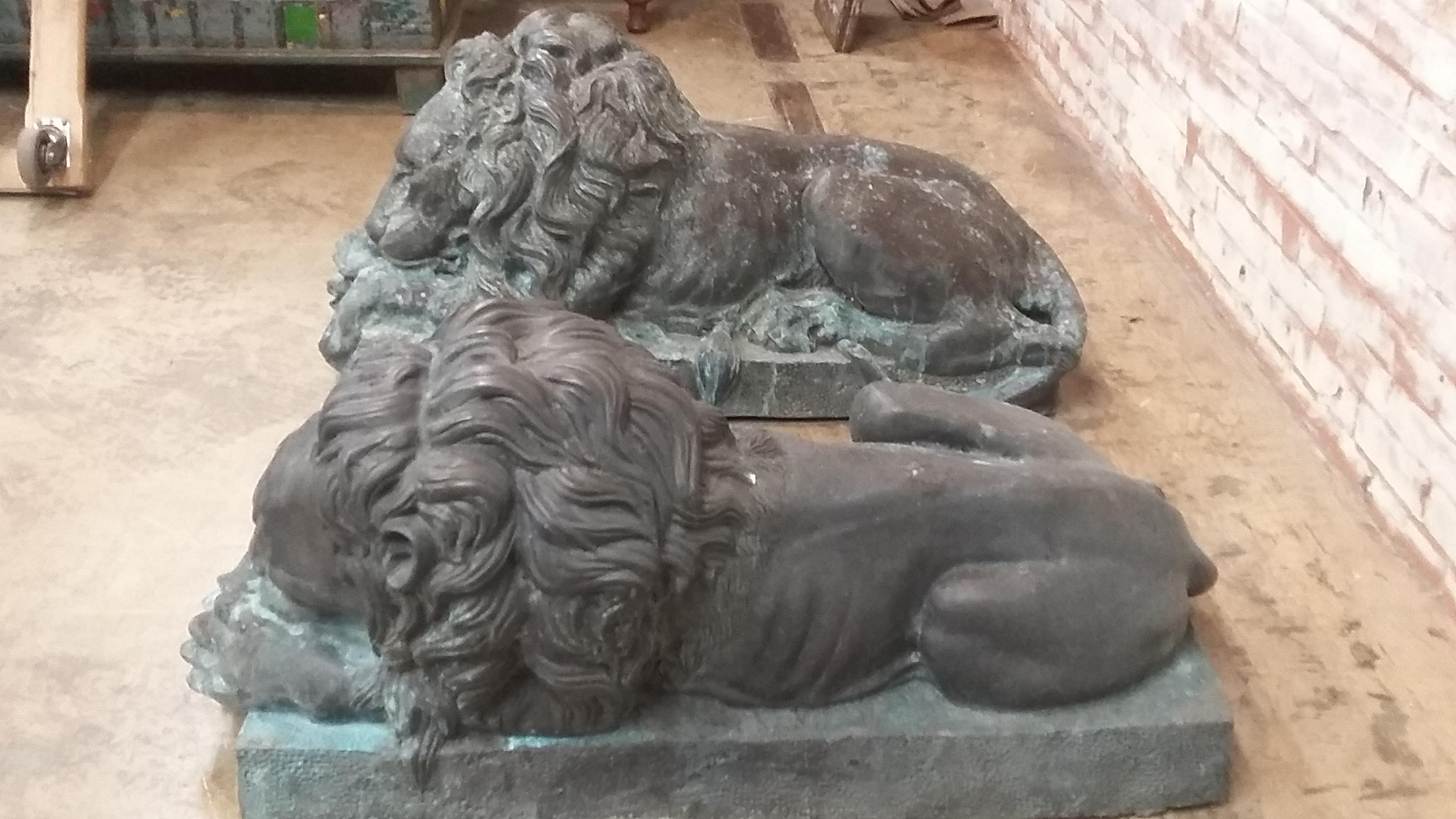 Great pair of bronze laying lions. A reproduction late 20th century pair that depicts both lions sleeping. A left and a right. Each is different. Acquired from upstate Connecticut estate. Originally made in Thailand. Very good condition with Verde