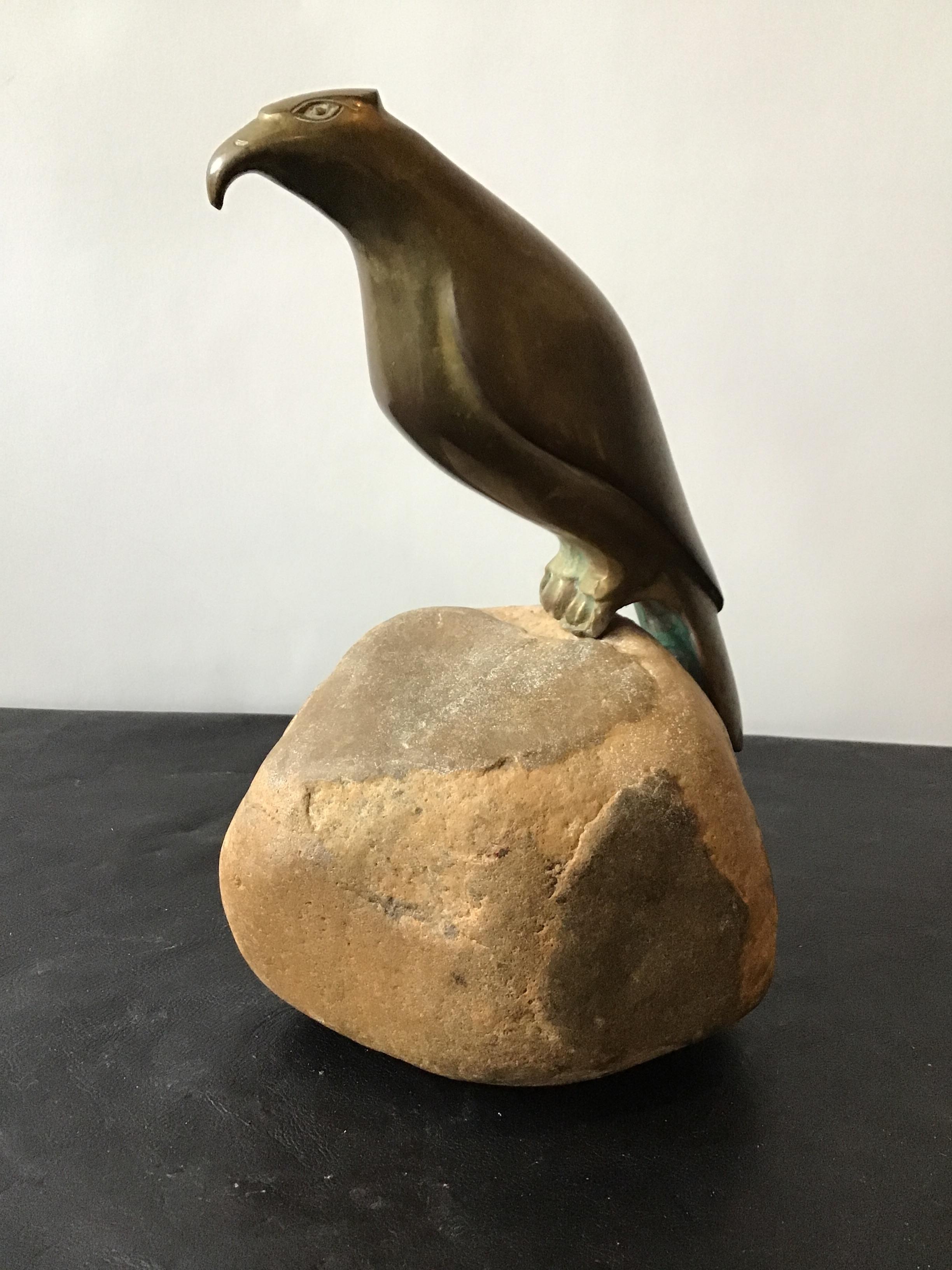 Bronze falcon perched on a rock.