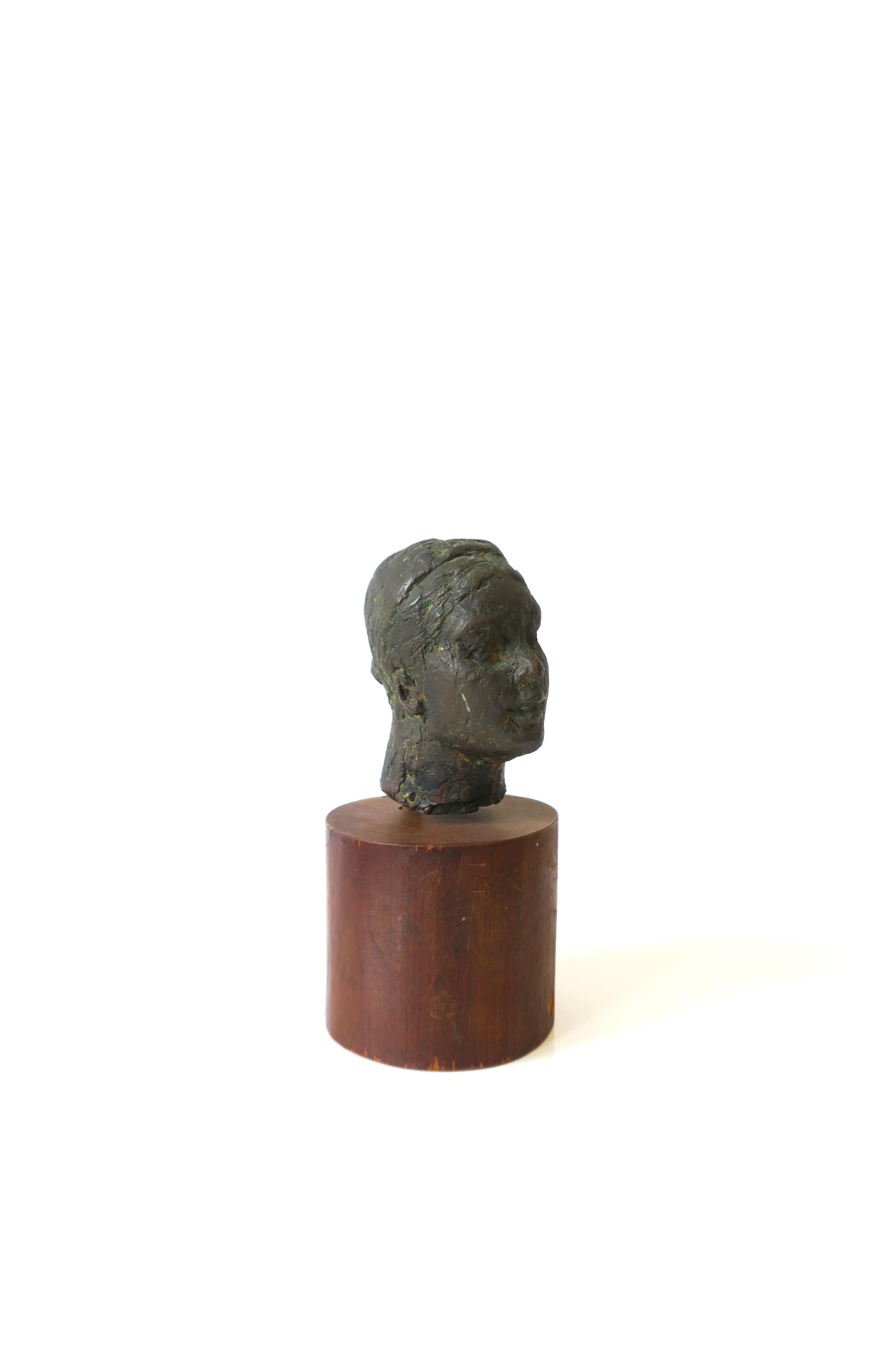 A beautiful, small, substantial bronze female head bust sculpture on cylindrical wood pedestal base, circa 20th century. Artist is unknow. Dimensions: 3.5