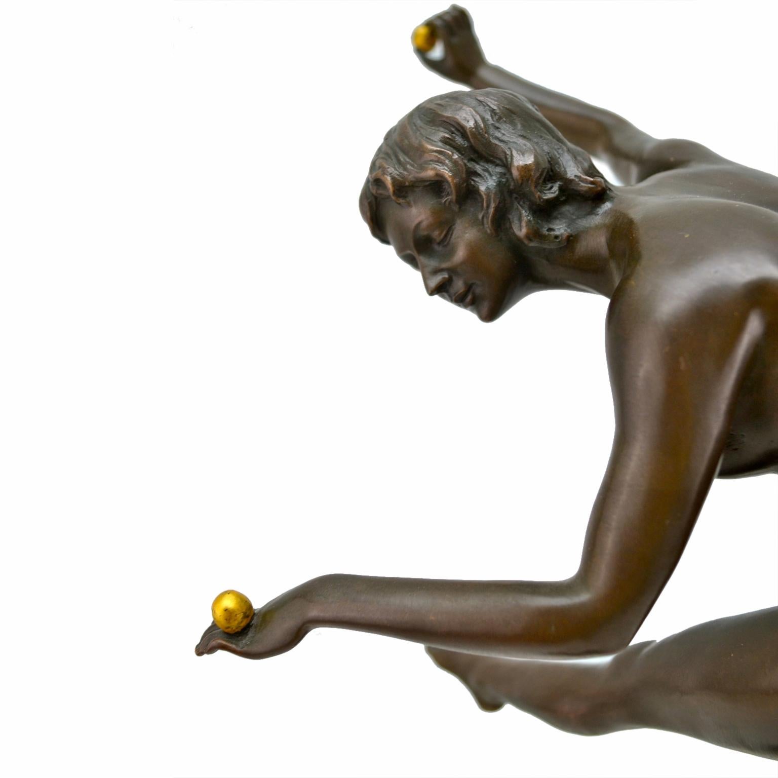 An Art Deco bronze figure with a dark brown patina after a model by Colinet. A young nude girl dances on top of a sphere her outstretched left leg and right arm balancing a gold ball. Signed Colinet but there are no foundry marks.
