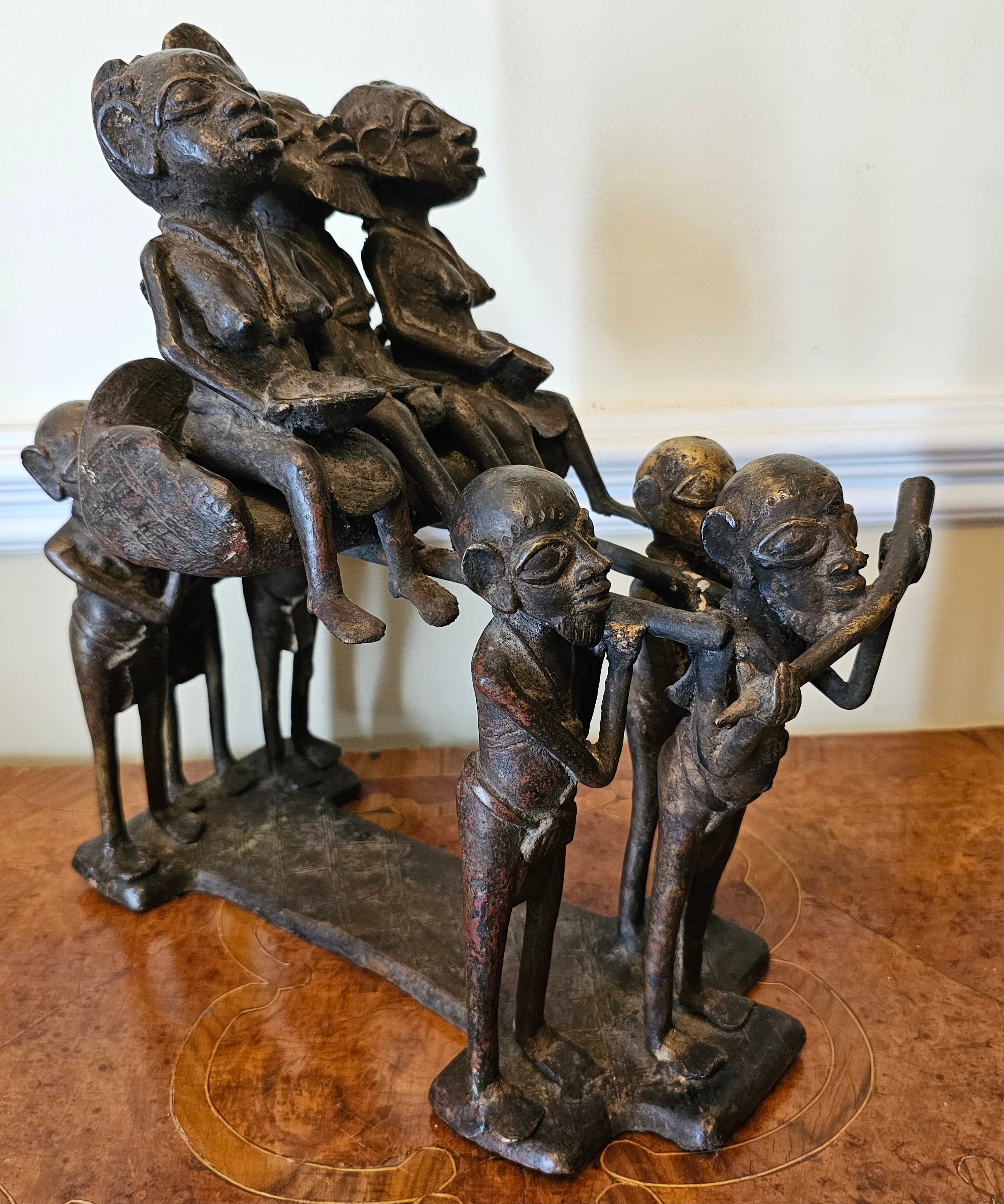An Early 20th century Bamoun Bronze sculpture. The art of bronze in african art at the service of the King.
The king, a bearded figure, a symbol of wisdom, sits in his carrier chair, accompanied by two of his wives and six other figures. All the