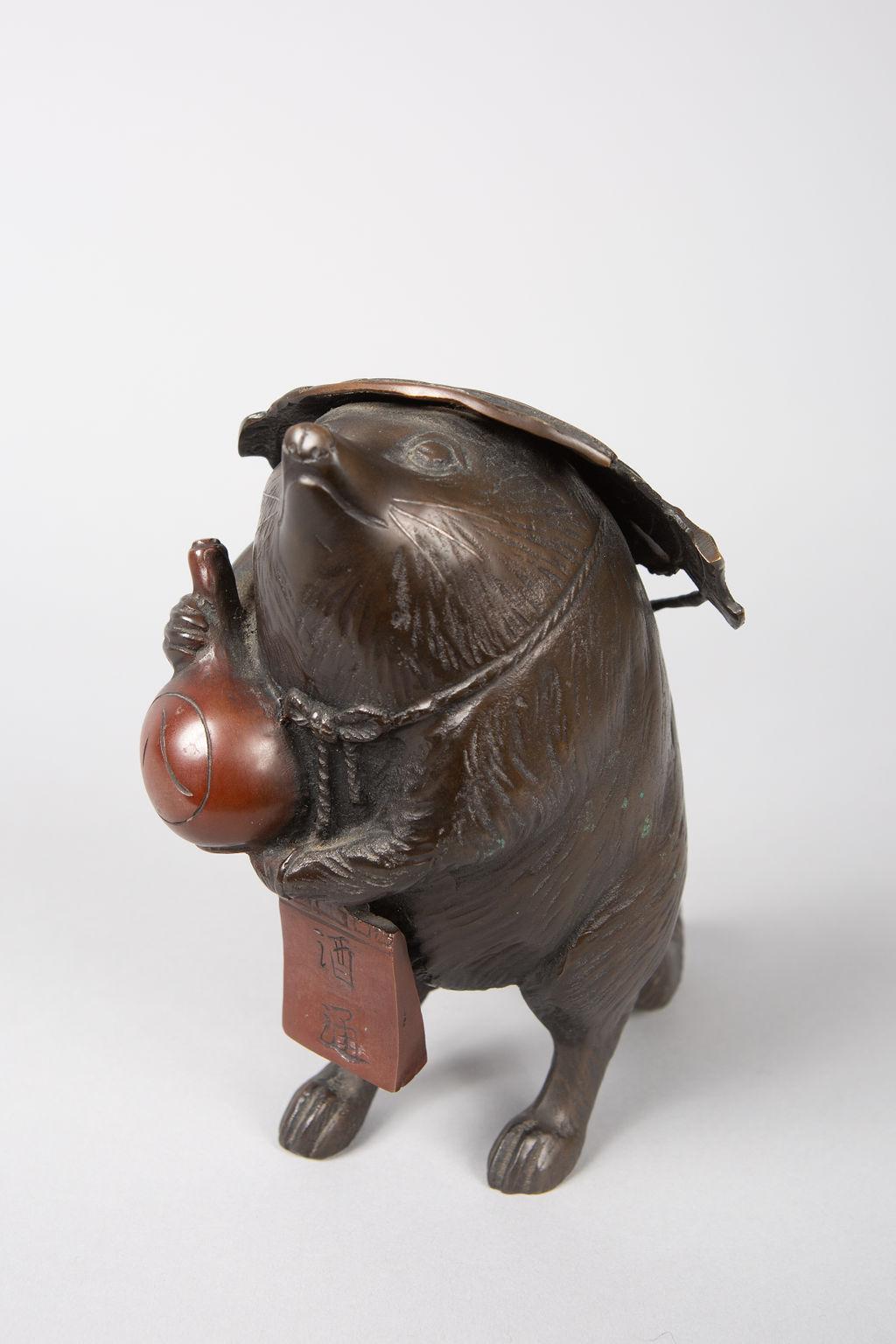 Japanese bronze sculpture of a badger, holding a sake bottle and a ledger. Great detail. Signature reads: Chikusen.