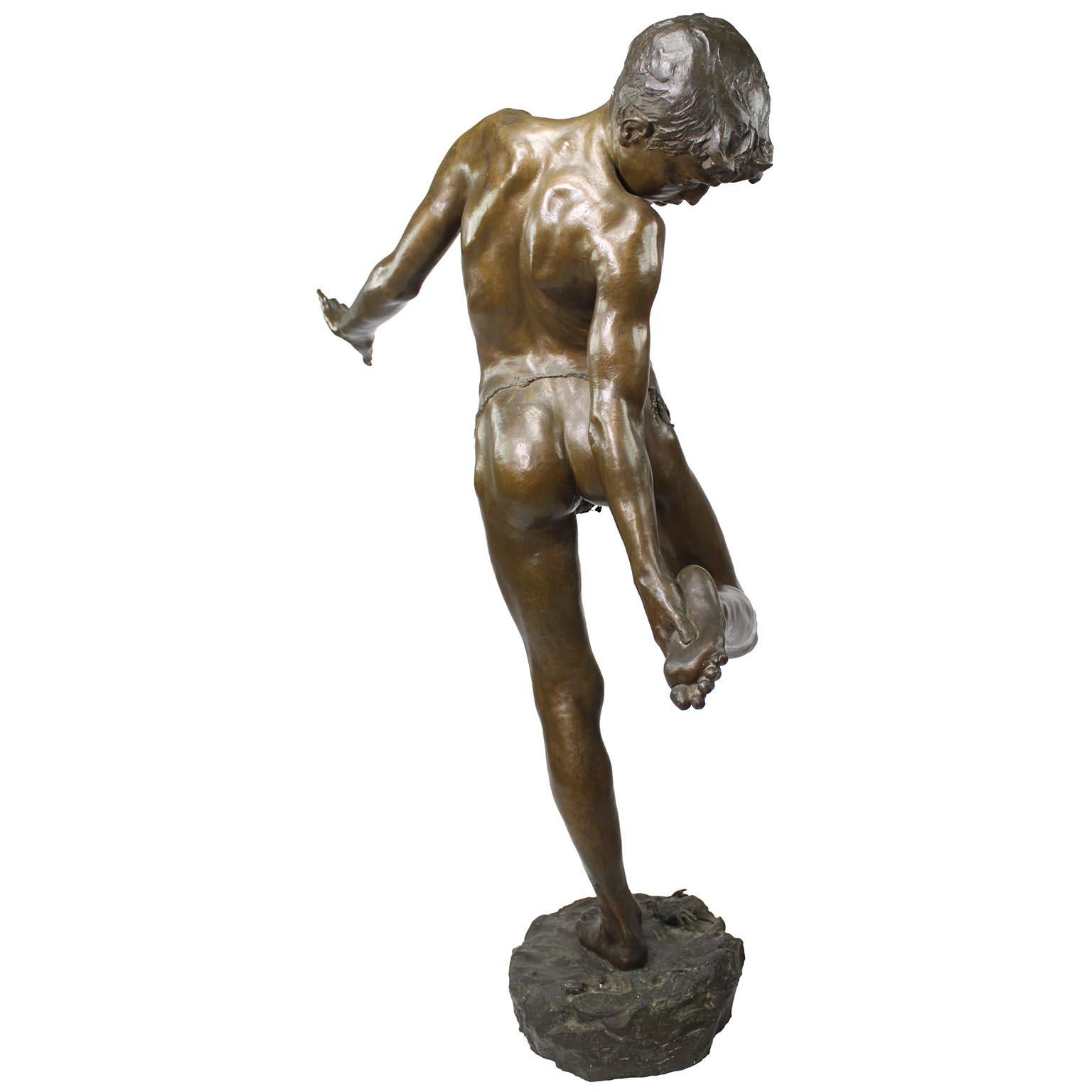Figura de bronce de un niño pisando un cangrejo titulada 