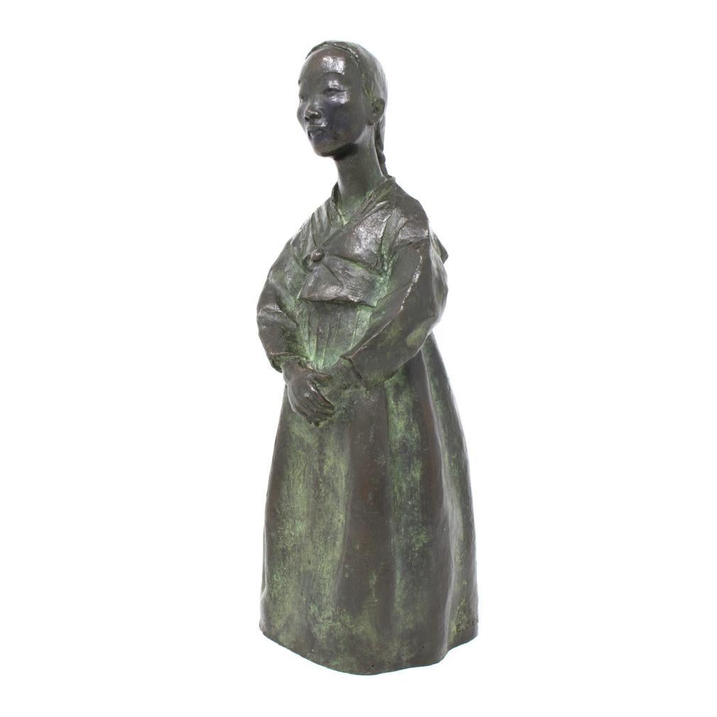 UH80304
Bronze Figure of a Korean Girl by Eudald Serra i Güell, circa 1940.
A heavily cast bronze figure of a standing young girl in traditional Korean Hanbok dress consisting of a jeogori jacket and a long chima skirt. Her long hair braided into a