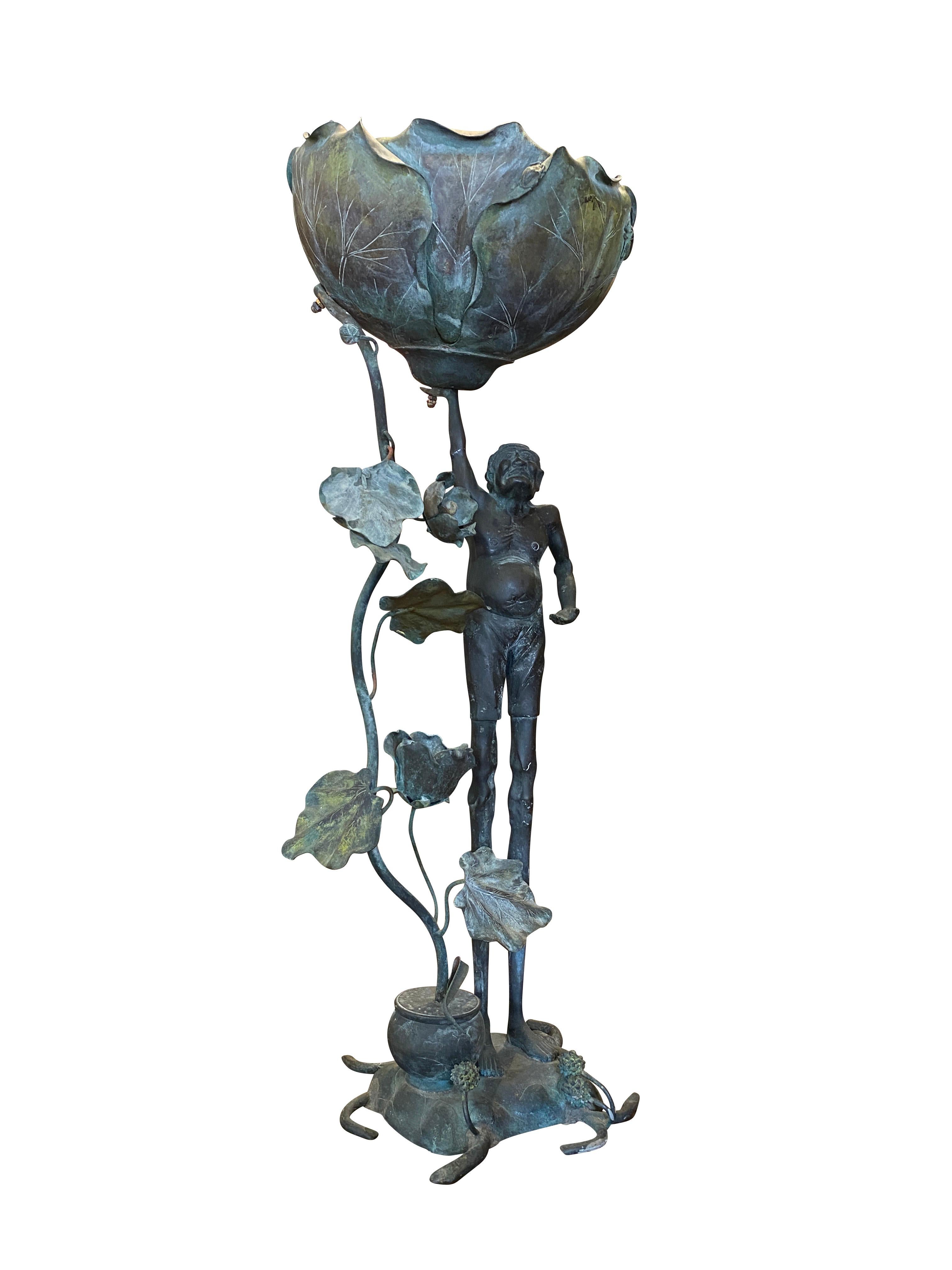 Ashinaga stands holding a fully open Lotus blossom with trailing vine and base with small urn the vine sprouts from.