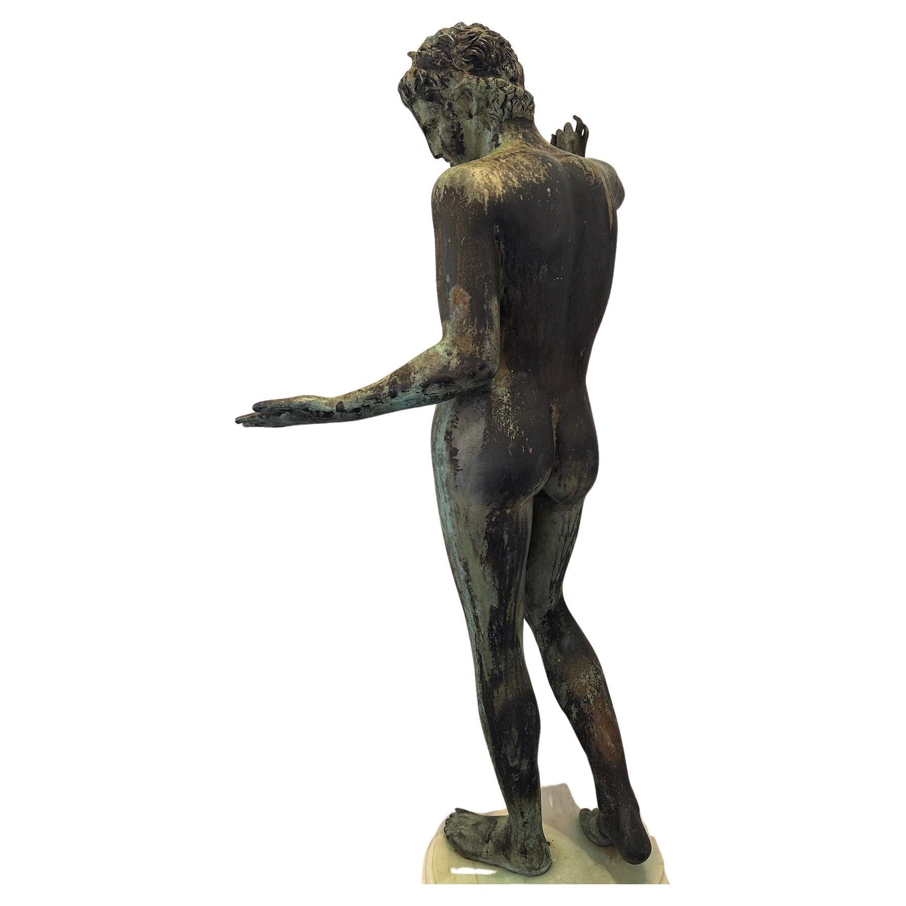 A verdigris bronze figure of a young male mounted on a marble plinth. in Grand Tour style.  
