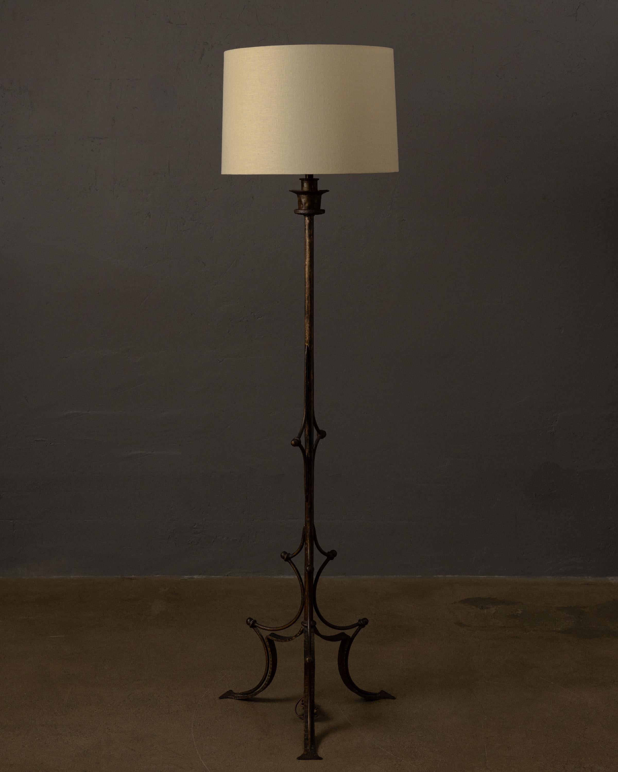 Un remarquable lampadaire en bronze présentant une élégante finition patinée et des détails sculpturaux en forme de volutes. La colonne centrale s'élève pour soutenir un abat-jour en lin nouvellement fabriqué, offrant un contraste raffiné avec la
