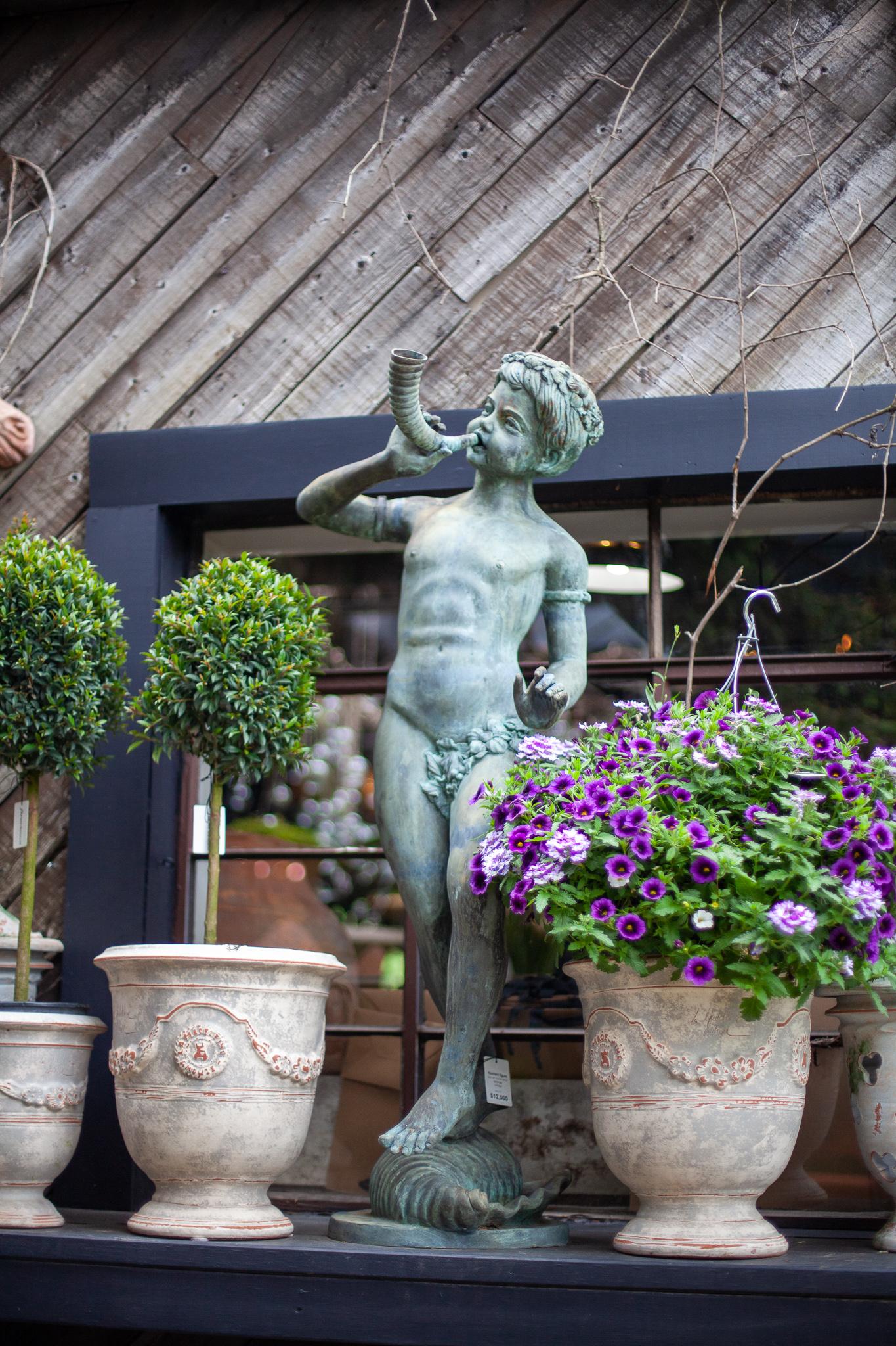 Ein verspielter Bronzebrunnen, dargestellt von einem jungen Mann, der ein Horn bläst, während er auf einer Muschelschale steht. Diese Gartenstatue ist die perfekte Ergänzung für jeden Garten als Springbrunnen oder Gartendekoration. Fleurdetroit