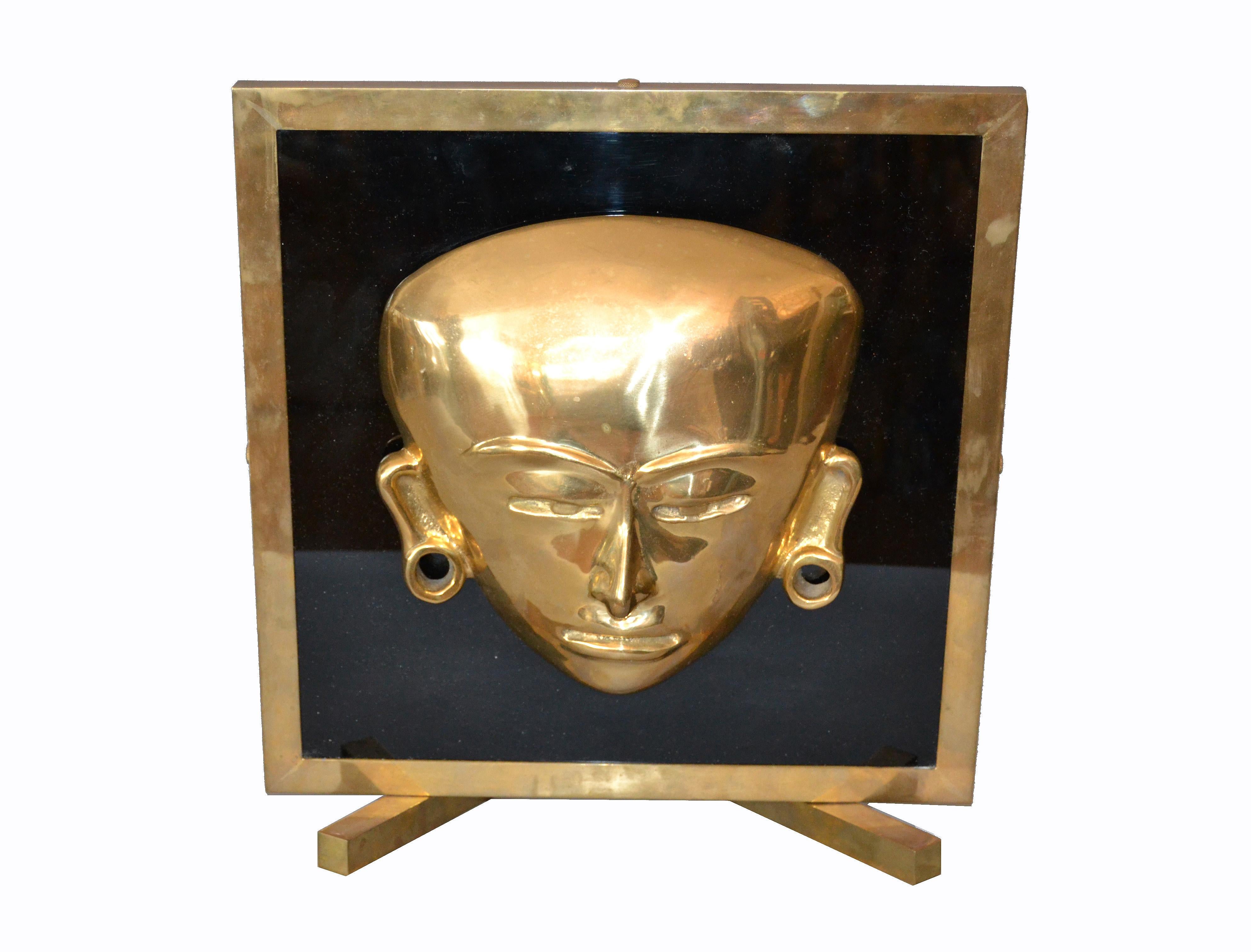 Decorative bronze framed brass African mask on black glass table art.
No markings.
It is very heavy and shows a warm patina.
