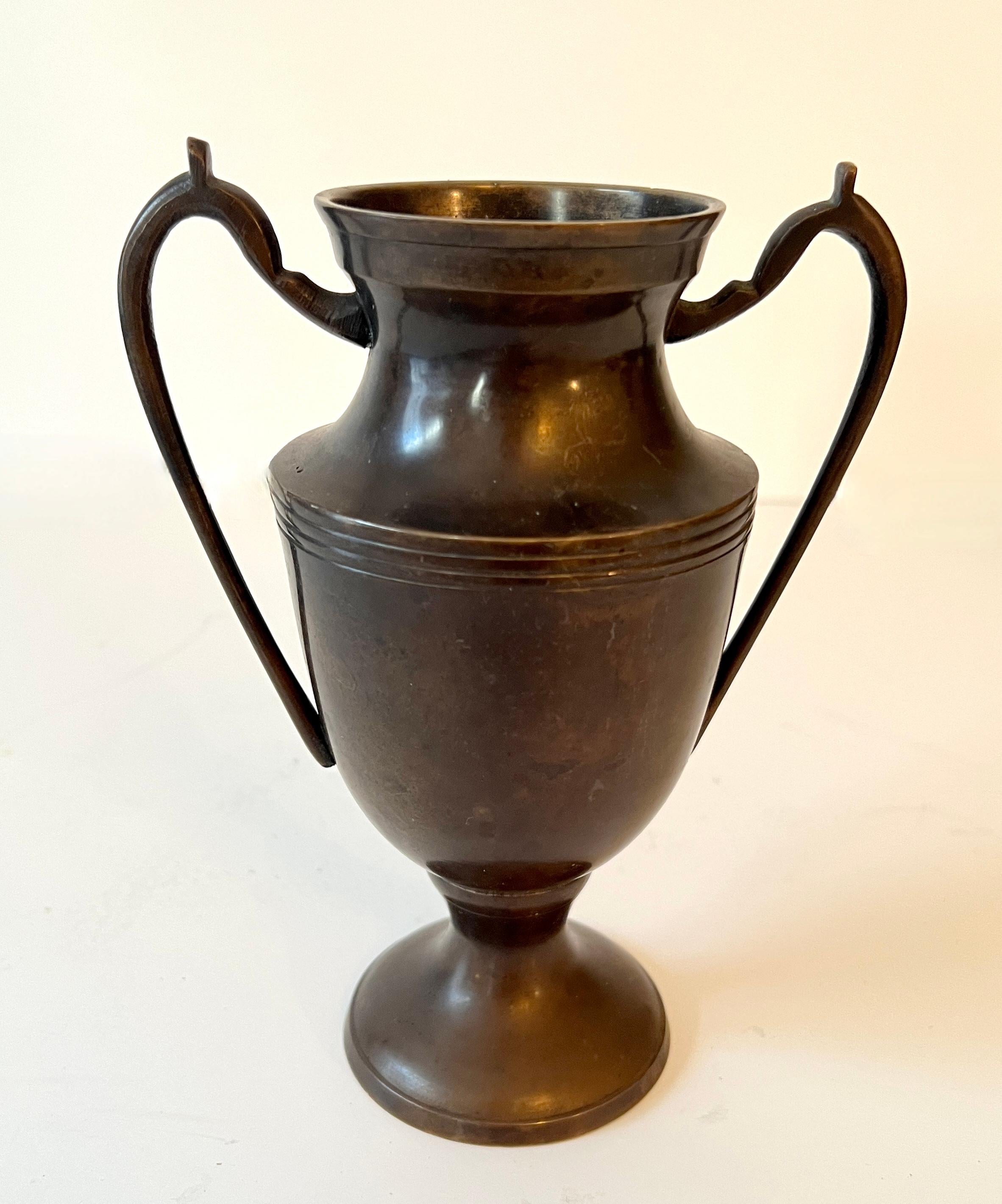 Un piccolo vaso o urna a forma di trofeo acquistato a Parigi.

Il vaso è un ottimo vaso per i fiori o come pezzo decorativo da posizionare da solo o su una mensola, una consolle, ecc.  La patina è bellissima e intatta.

Tieni presente che lo