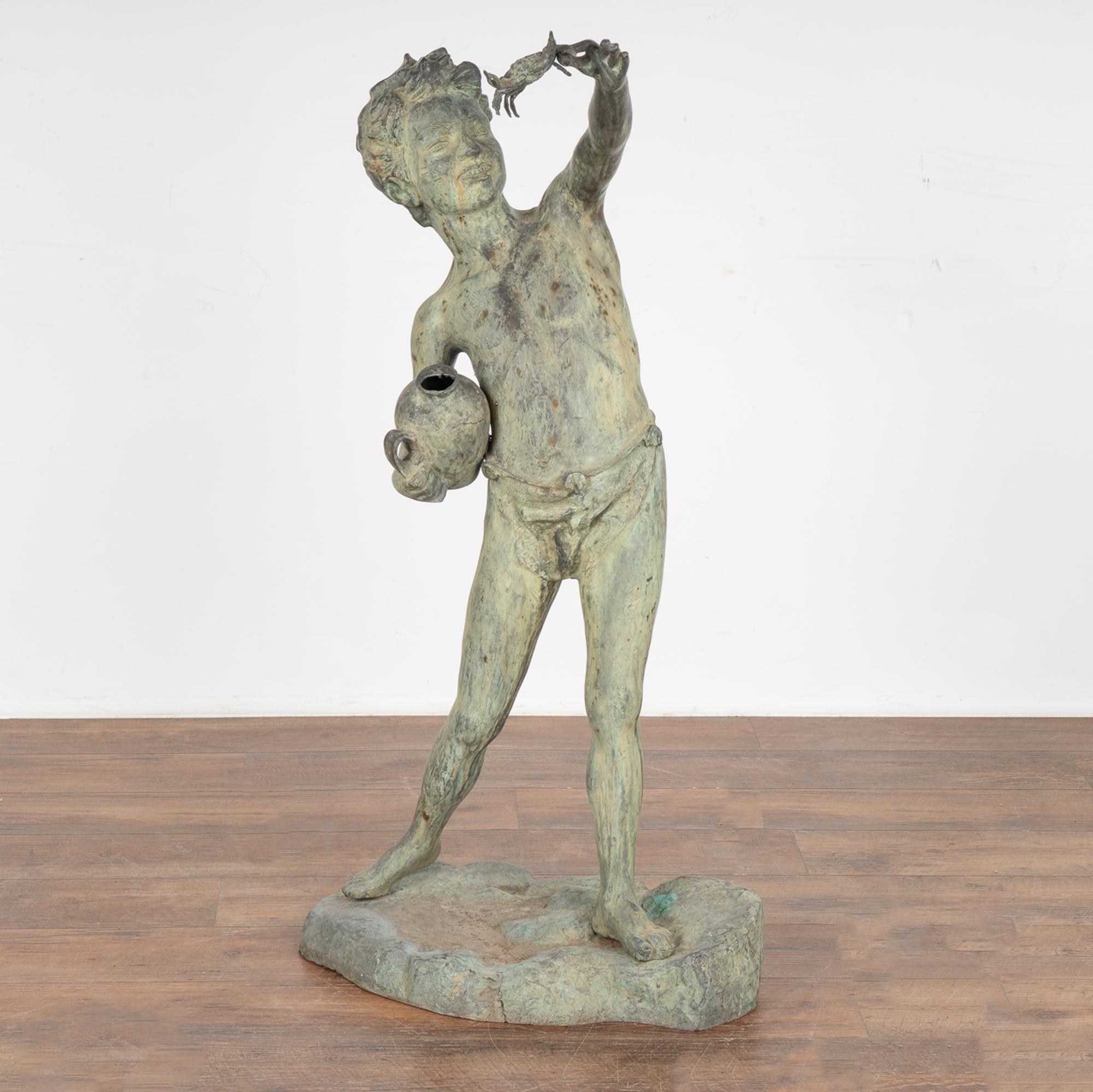 Bronze garden figure of standing young boy with a crab in one hand and a jar in the other. 
Verdigris aged patina from years outdoors.
Sold in original used condition. Any nicks, scratches, dings, cracks are refective of age and use and do not