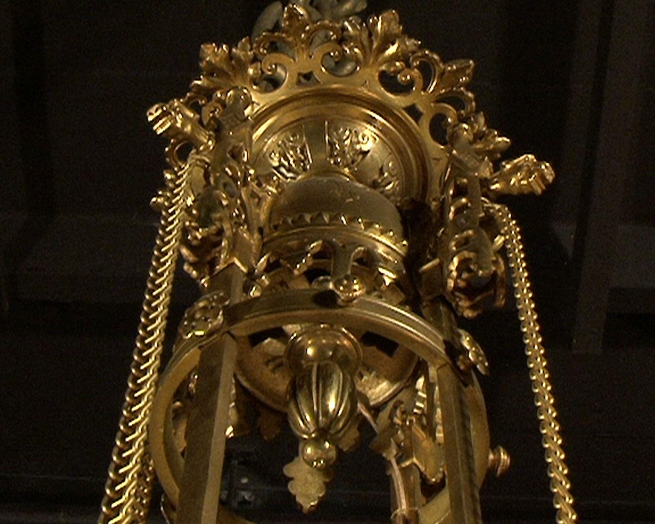 This gilt bronze chandelier has eight branches which take the form of glassware and candles and surround a semi spherical decorated with glass gemstones. Result of a very careful work, this chandelier has incised decorations of fleur de lis, crosses