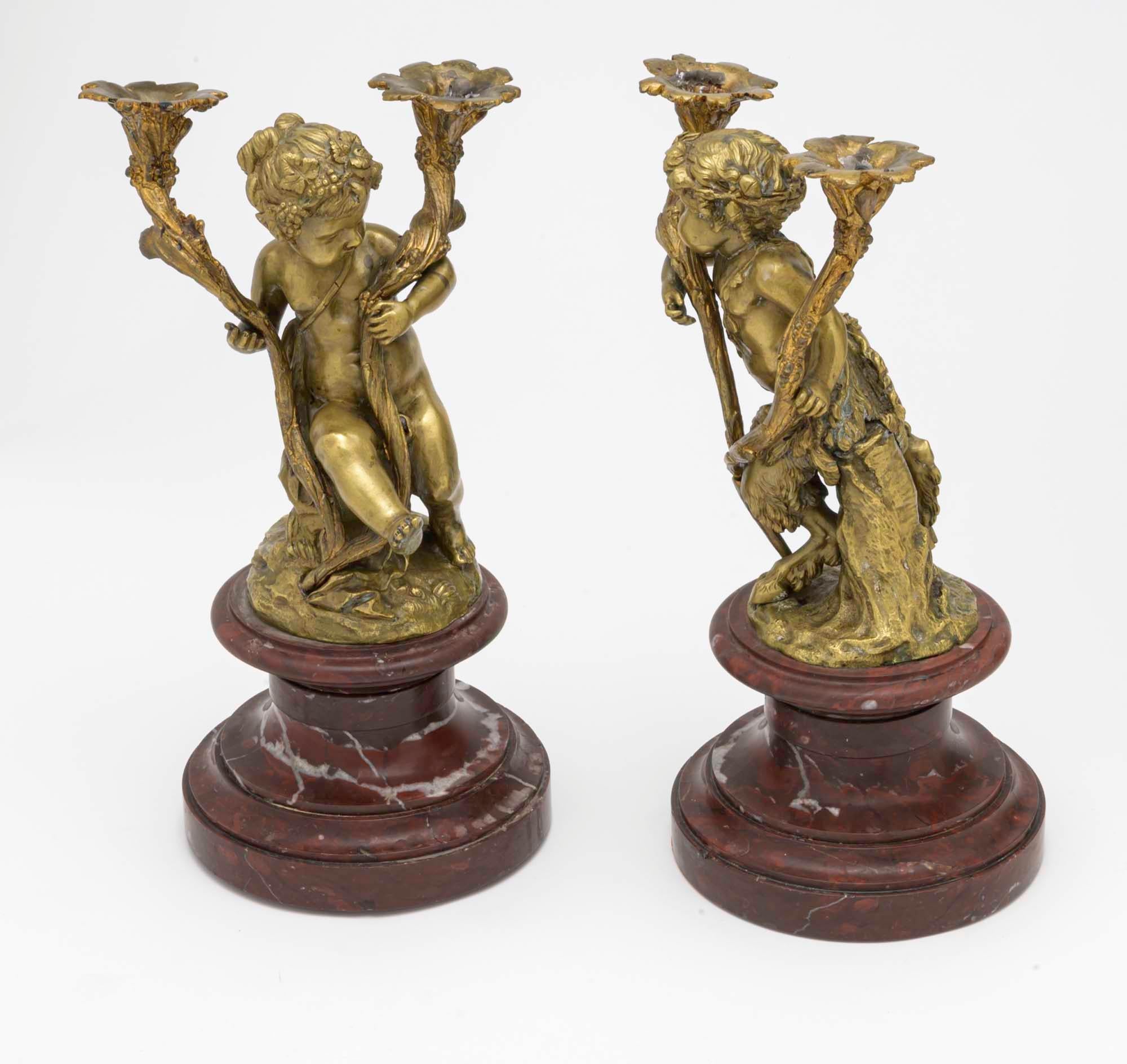 Charming pair of bronze gilt putti and pan candlesticks. They sit on rose colored round marble plinth.
Properly facing each other, holding floral stems for candles. Beautifully executed with superb details.
Approximately 14” in height each.
  