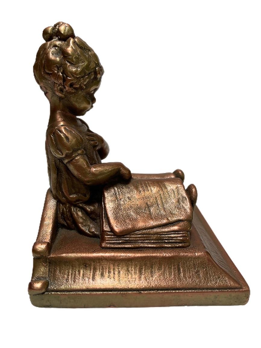 A pair of heavy, bronze bookends featuring a girl reading an oversized book. Her hair is up in a bun as she points to a passage in the novel with one hand and covers her heart with the other. She appears to be sitting upon a bed.

Please note that