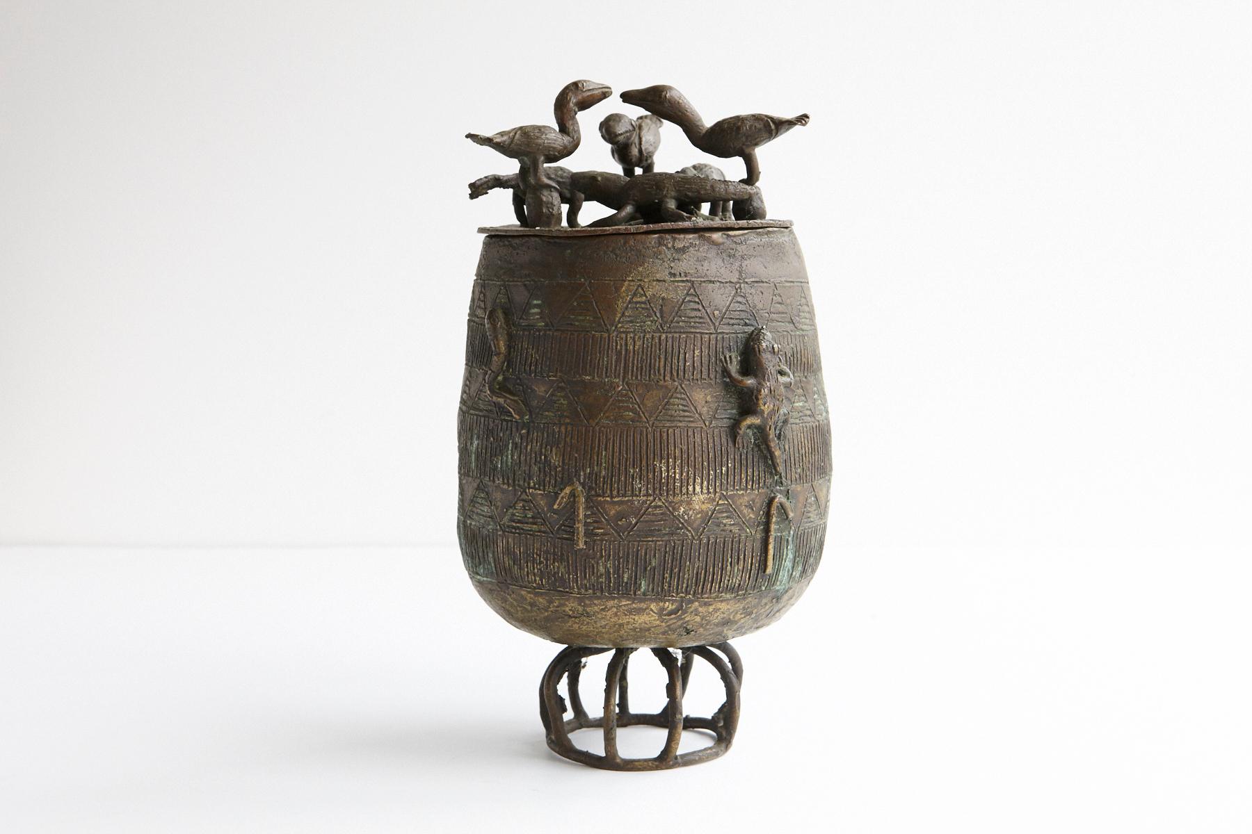 A beautiful bronze vessel, lidded ovoid pot on a circular support, made by the Asante People, Ghana. Nicely cast lid with 7 figures in the form of animals and reptiles are depicted on the side of the vessel crawling up the edge.
The so-called 