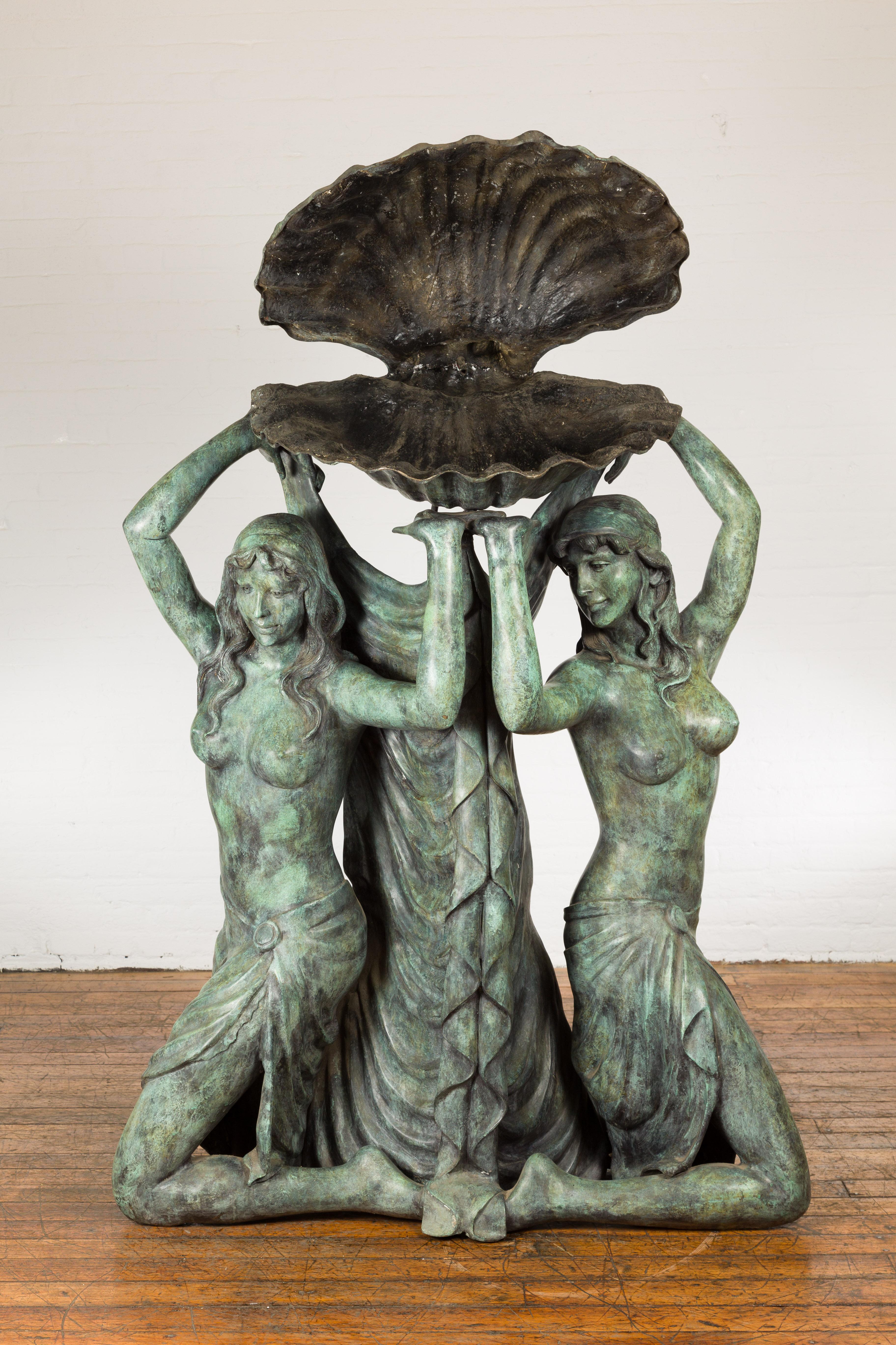 Fontaine en bronze coulé à la cire perdue, d'inspiration gréco-romaine, représentant trois nymphes tenant un grand coquillage au-dessus de leur tête. Plongez dans la beauté éthérée de cette fontaine en bronze d'inspiration gréco-romaine, qui met en