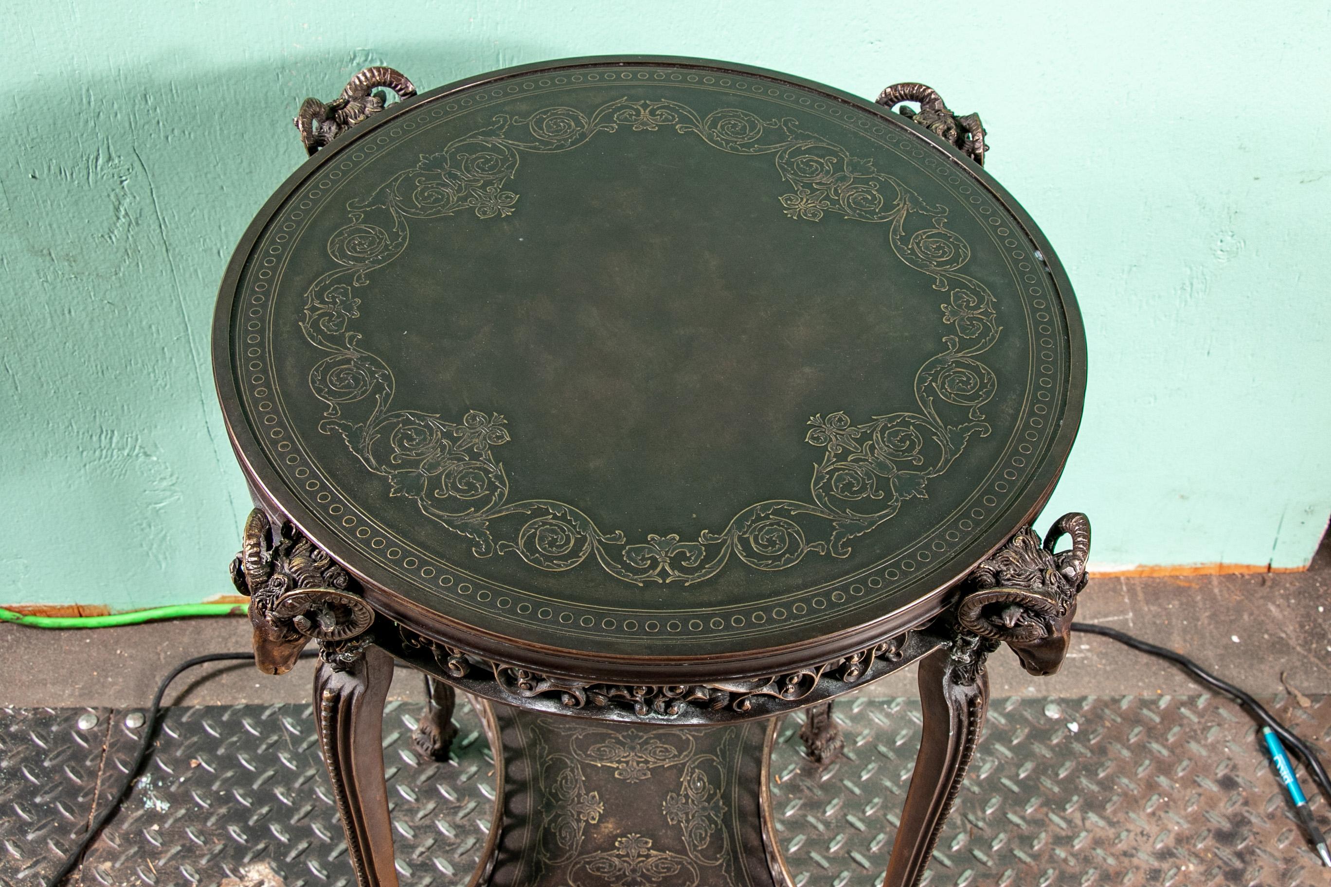 A circular top with scrolled decoration and openwork scrolled frieze.
A shaped lower shelf with leafy decoration and a gallery. 
Raised on tall curved legs with ram's heads at top and hoof feet. 

Condition: well presented in good condition.