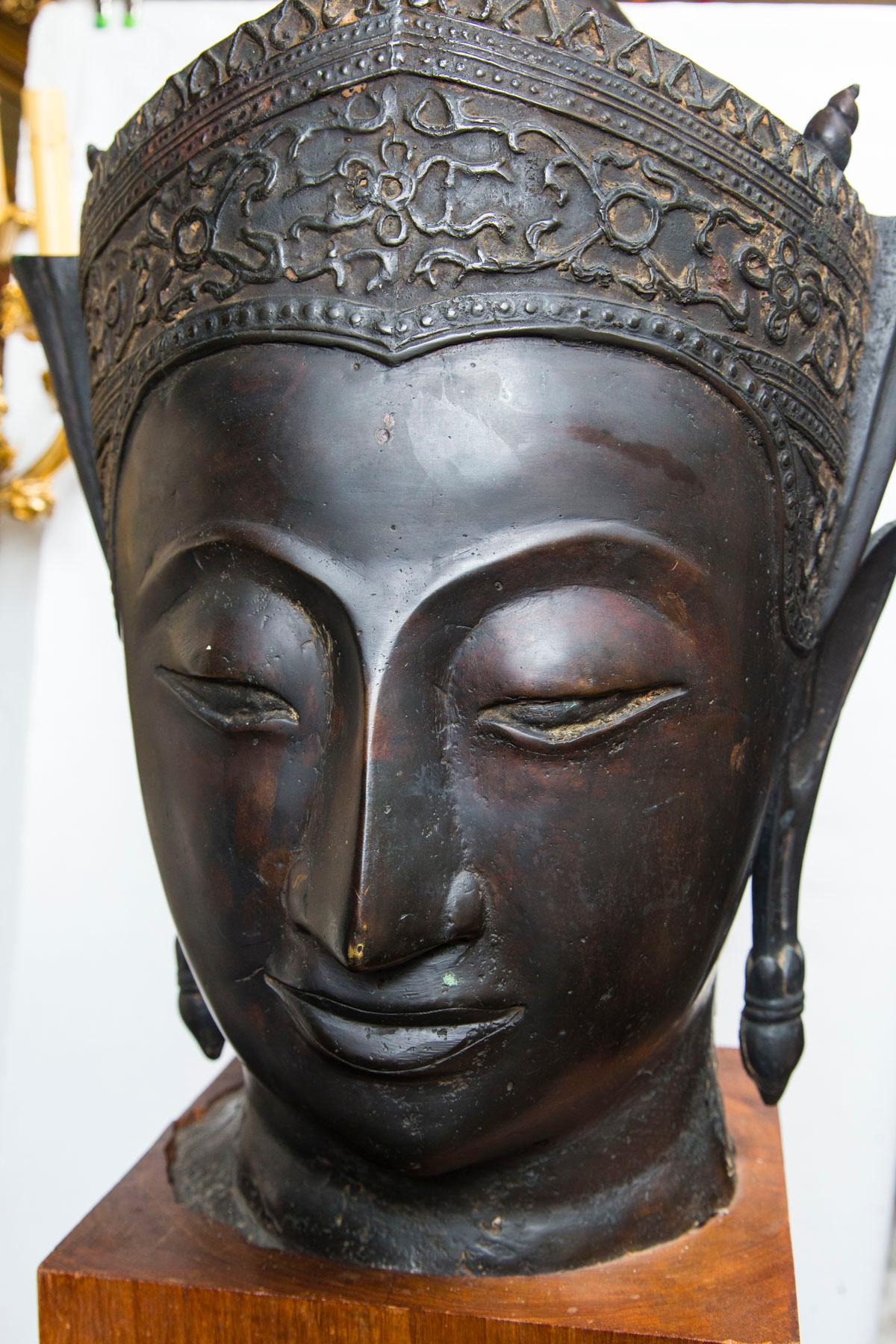 In the Thai style, with dark brown patina. Attached to a wooden block base. The head, itself is 24 inches tall. The base measures 10 x 10 x 9.5 tall.
 