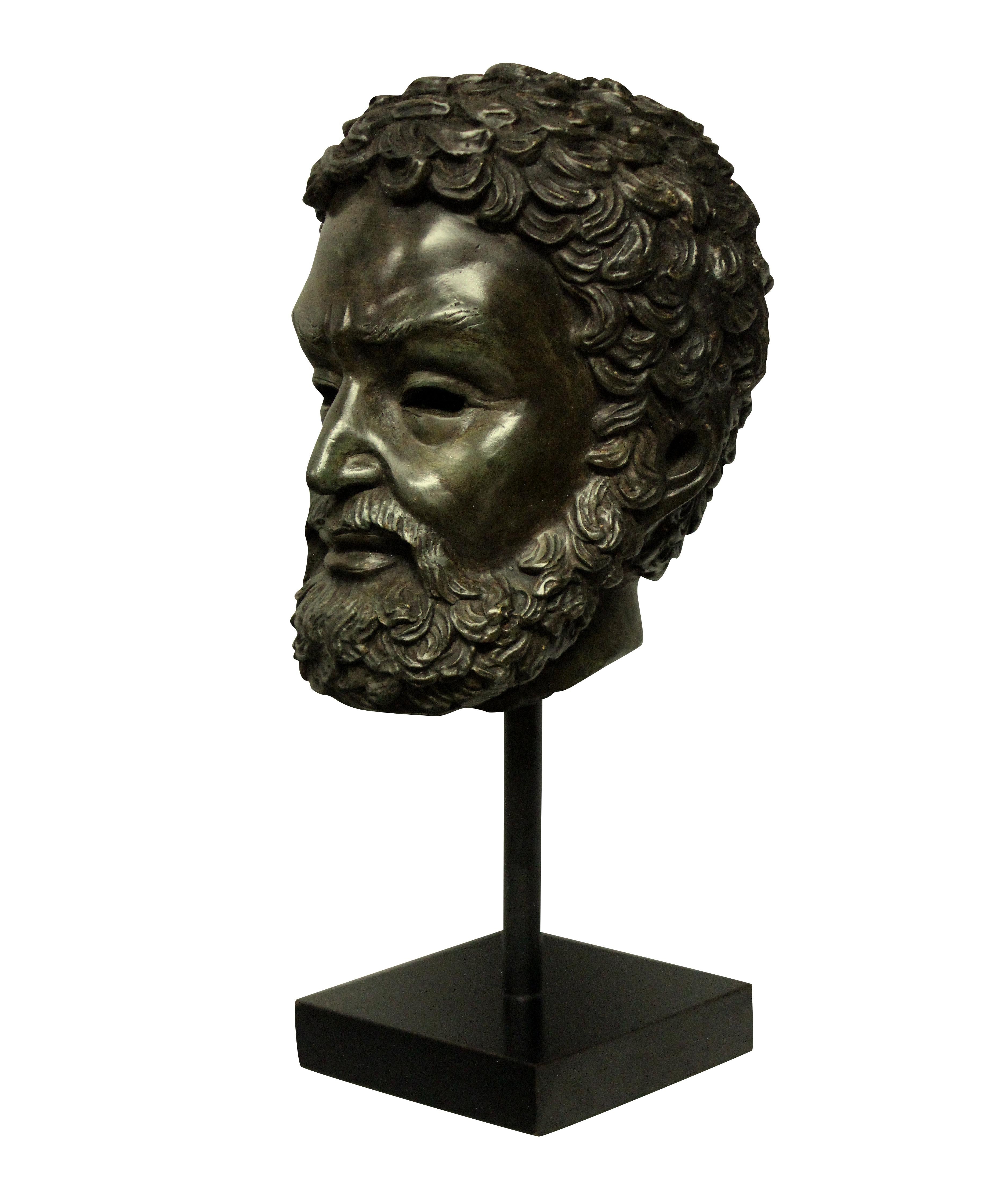 An English bronze head of Zeus, mounted on an ebonised stand.