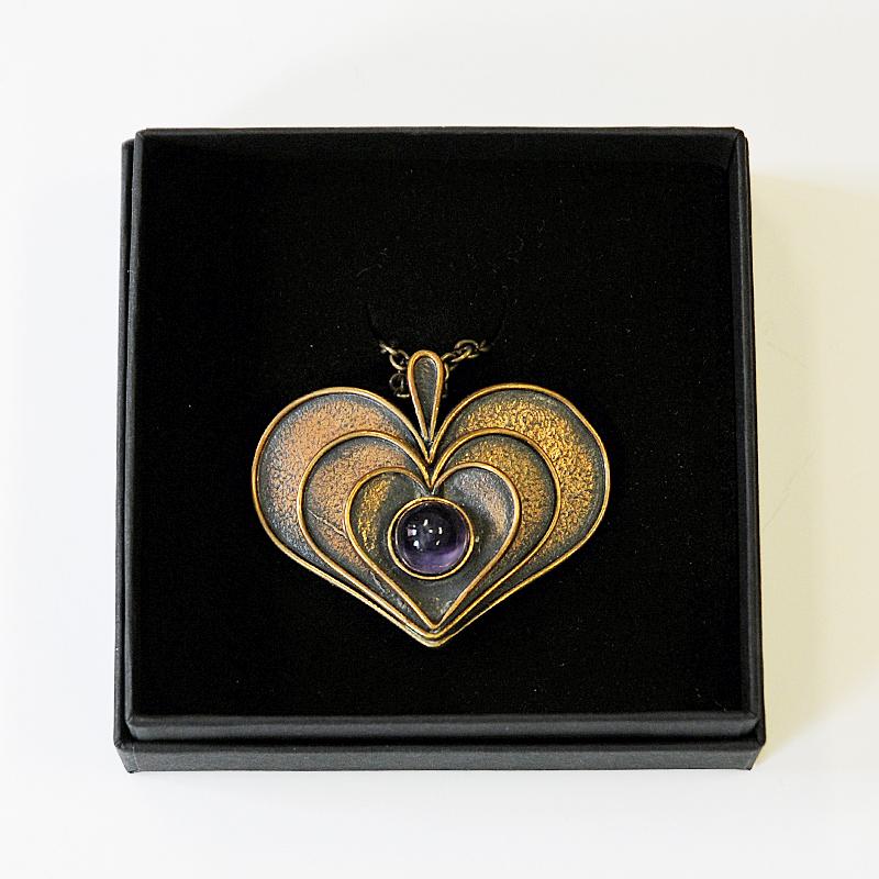 Beautiful vintage heart pendant of bronze decorated with a Classic purple stone in the middle. Designed by finnish midcentury jewelry designer Pentti Sarpaneva (1925-1978). This vintage pendant has three layers of hearts lying on top of each other.