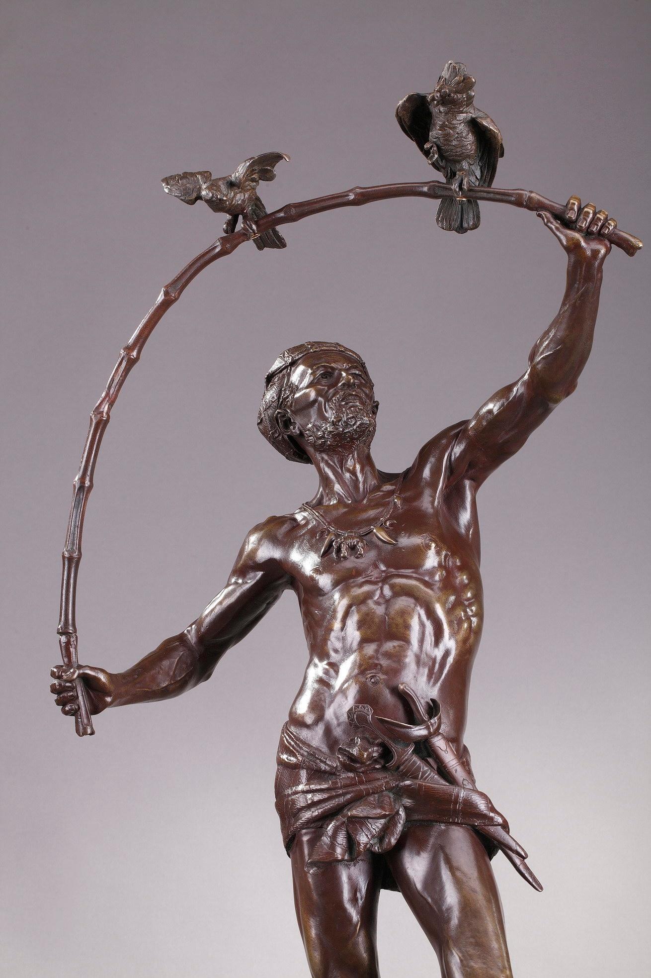 Grande statue en bronze représentant un hindou attrapeur d'oiseaux, réalisée par le sculpteur et médailliste belge Auguste de Wever. Il porte un ruban et une draperie soutenant une petite épée. Son collier est orné d'un médaillon en forme