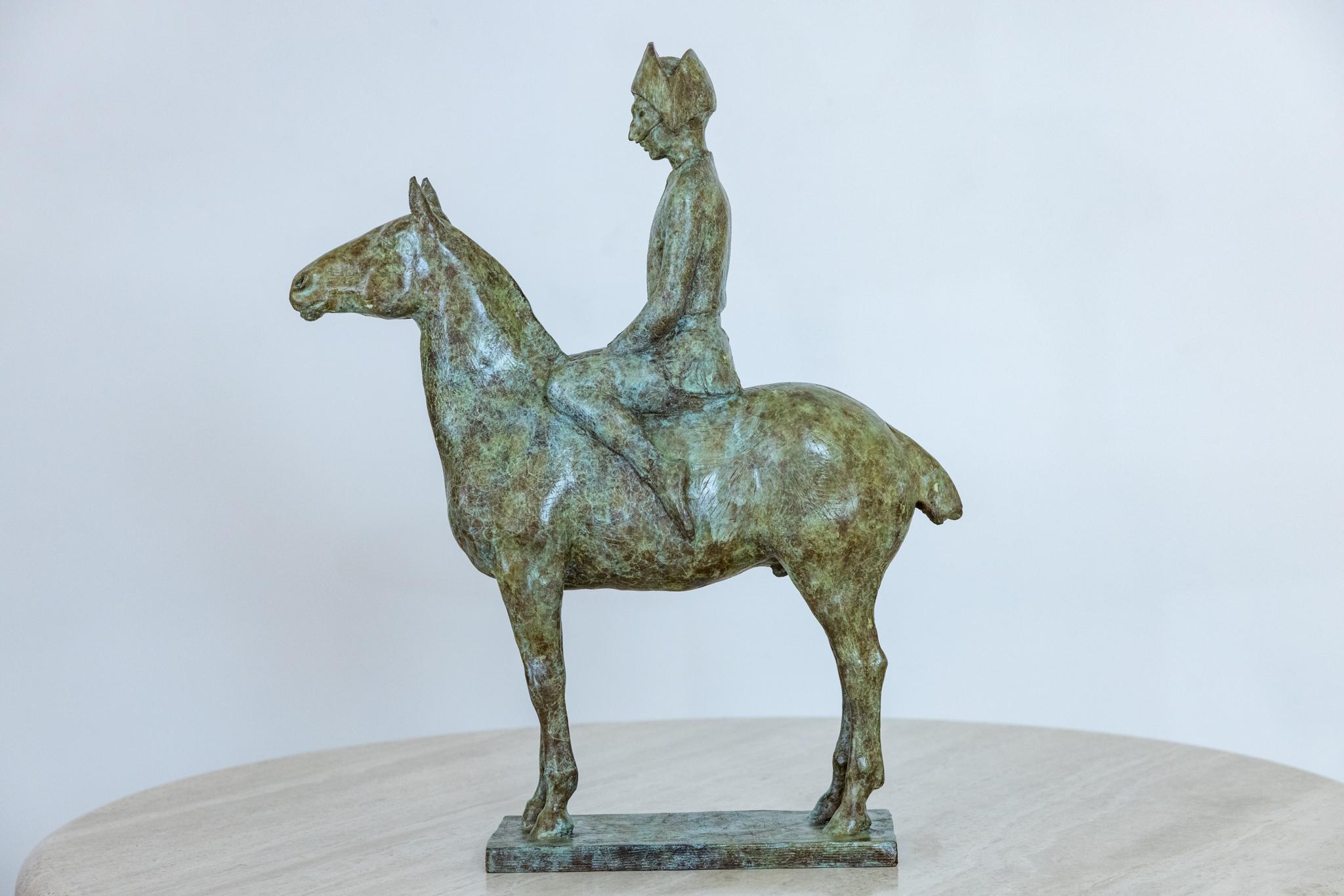 This is a striking bronze sculpture featuring a prominently masked figure much like a harlequin on a horse. the majestic horse stands proud with the rider sitting upright and ready to dash off.  The light application of patina allows for the natural