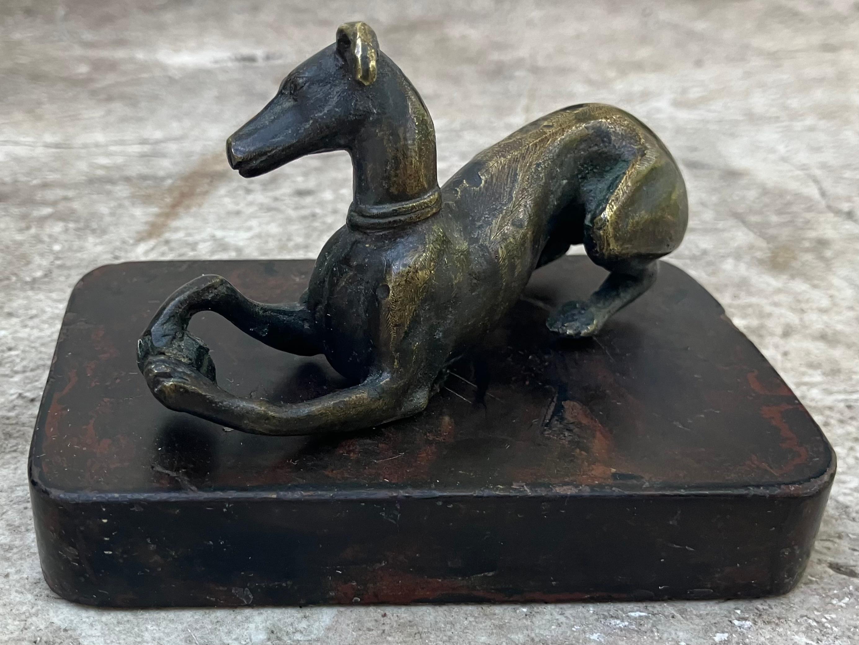 Sculpture en bronze représentant un chien avec une balle. Chien de chasse italien ancien en bronze, représenté en train de jouer avec une balle entre ses pattes avant, sur une basse base romaine Rosso Antico. 
