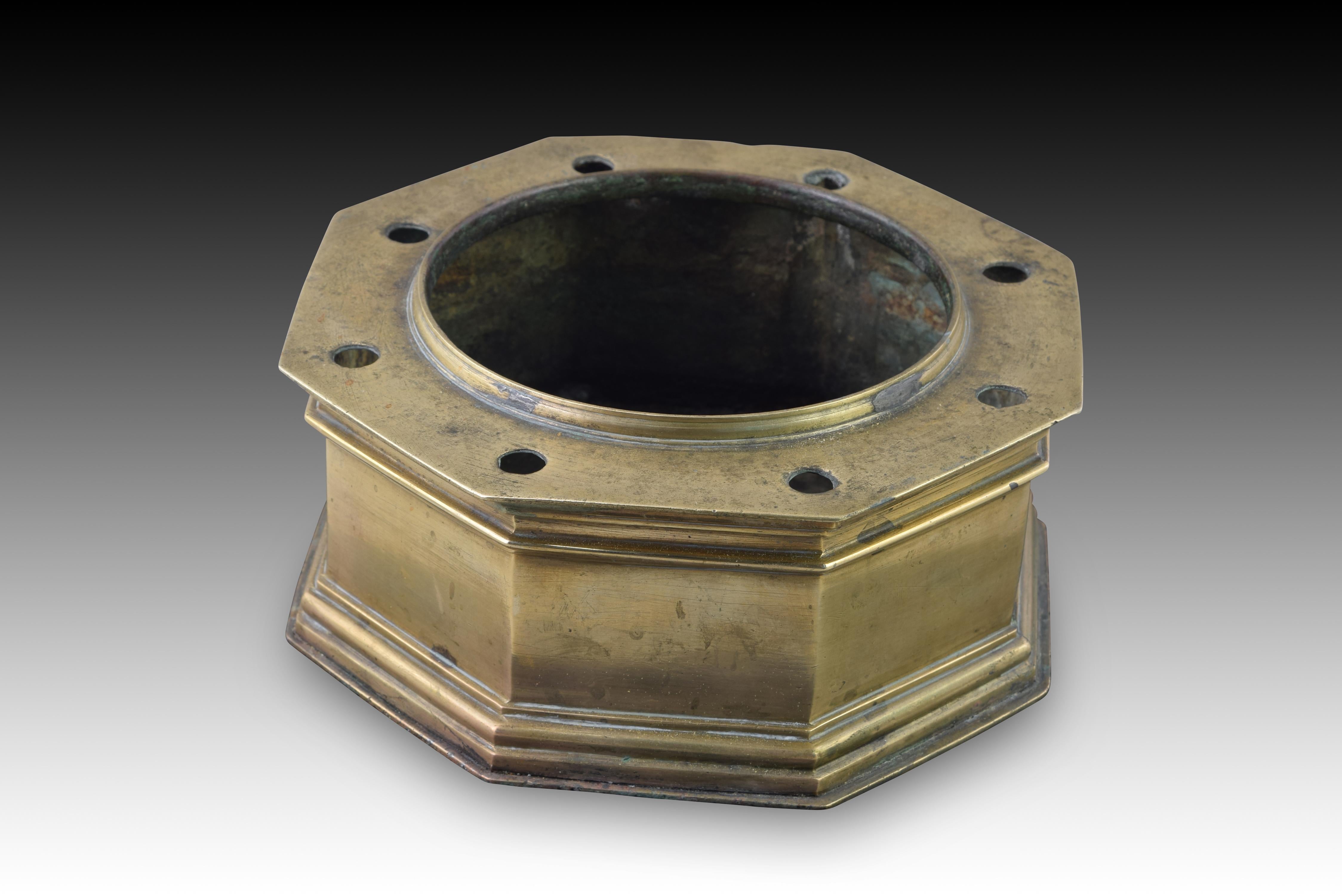 Bronze inkwell. Spain, 17th century. 
Inkwell made of octagonal bronze with eight small holes and one larger one in the center of the upper part that has a flat base and decoration on its fronts based on moldings of different shapes and widths, all