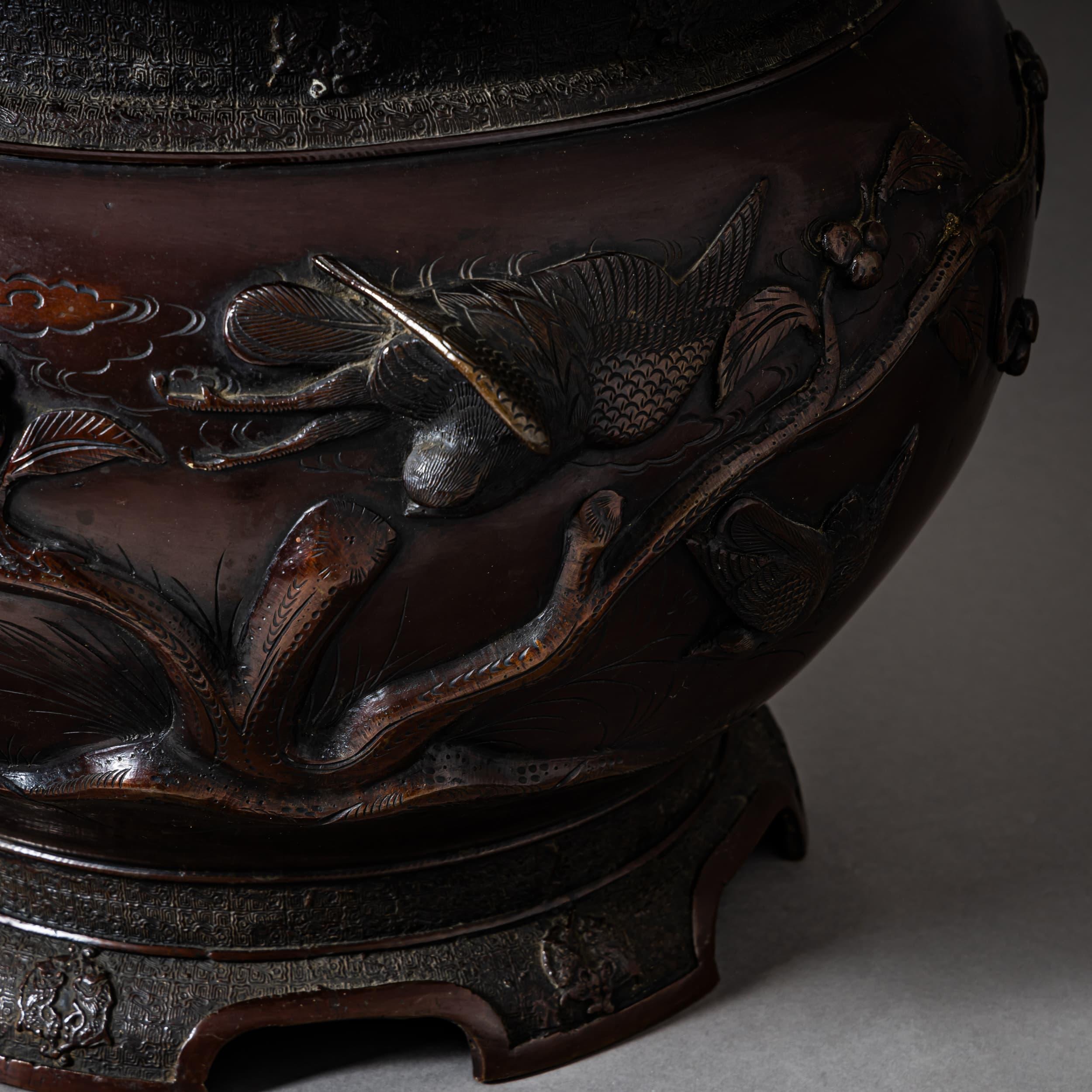 Finely crafted Japanese bronze jardinière with a bulbous body. The surface is richly decorated in relief with swallows in flight, tree branches, berries, and foliage—a naturalistic motif typical of Meiji-period metalwork.