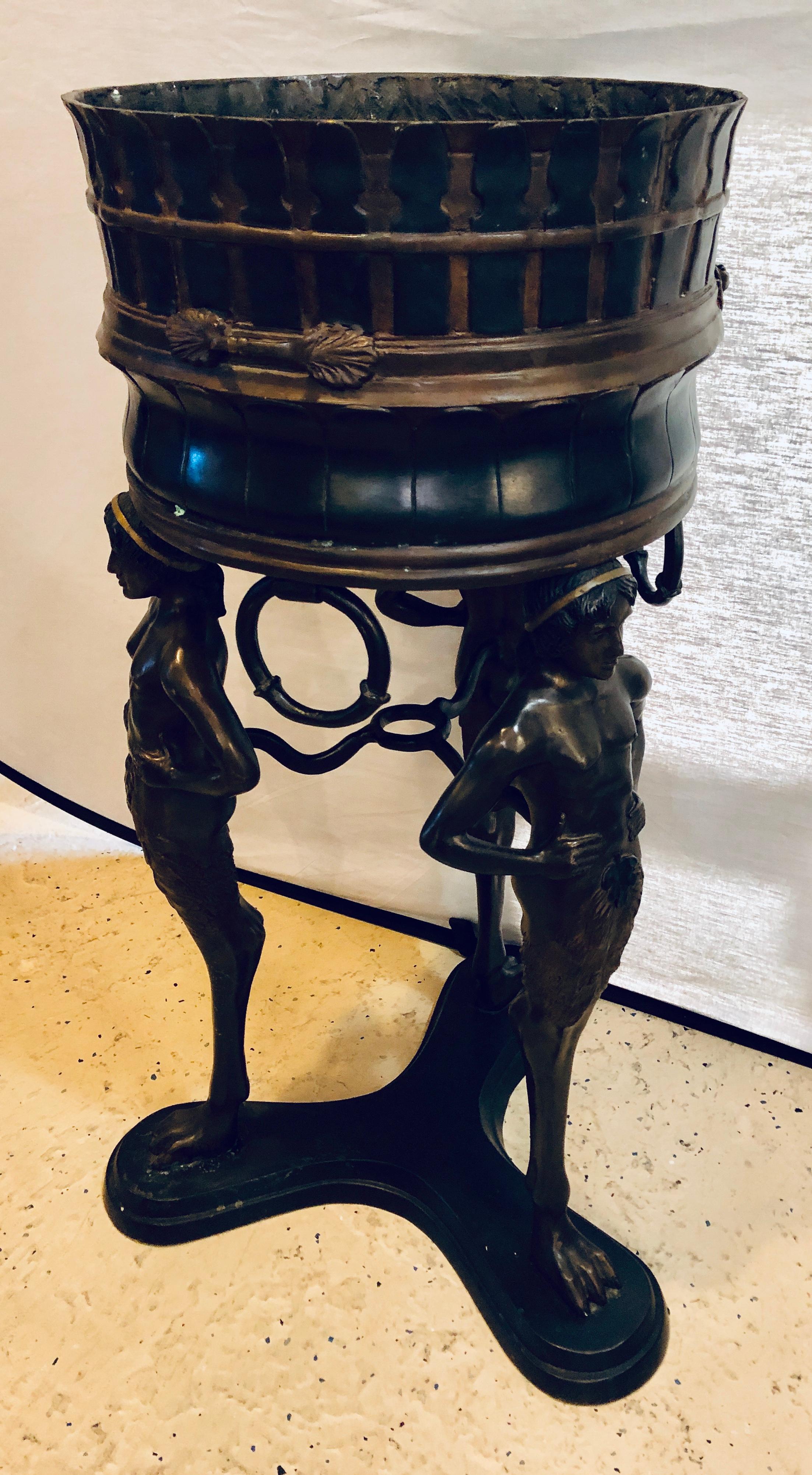 A bronze jardinière, brazier or standing planter depicting a group of three full figured ladies. Signed Joy Michoal This large and impressive planter or jardinière has three large naked water bearers, each covered by a fig leaf, balancing a planter