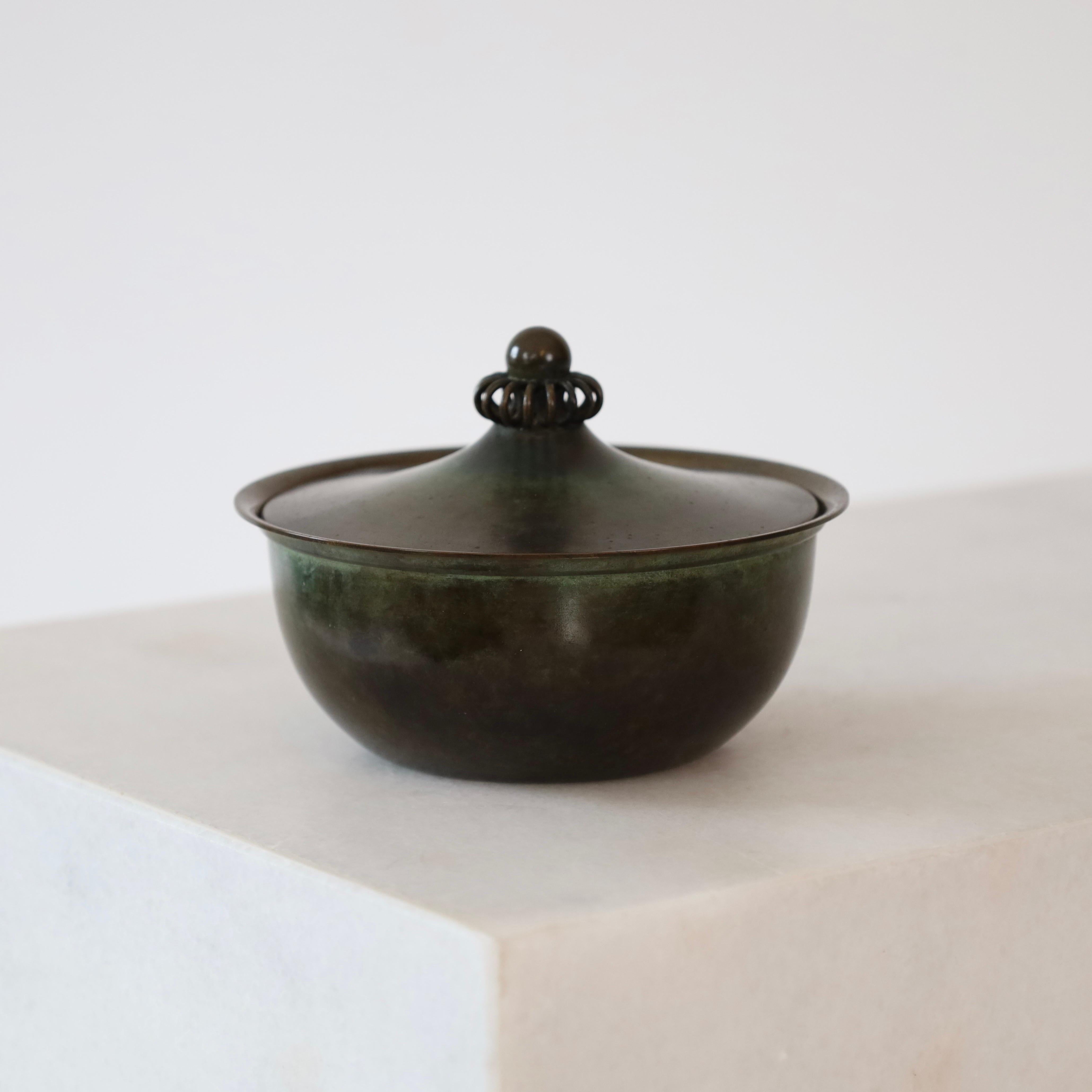 Rare boîte à bijoux ronde en bronze clair conçue par Just Andersen dans les années 1930. C'est une jolie petite chose pour un endroit magnifique.

* Une jarre ronde en bronze et éclairée avec des ornements
* Designer : Just Andersen
* Modèle : LB