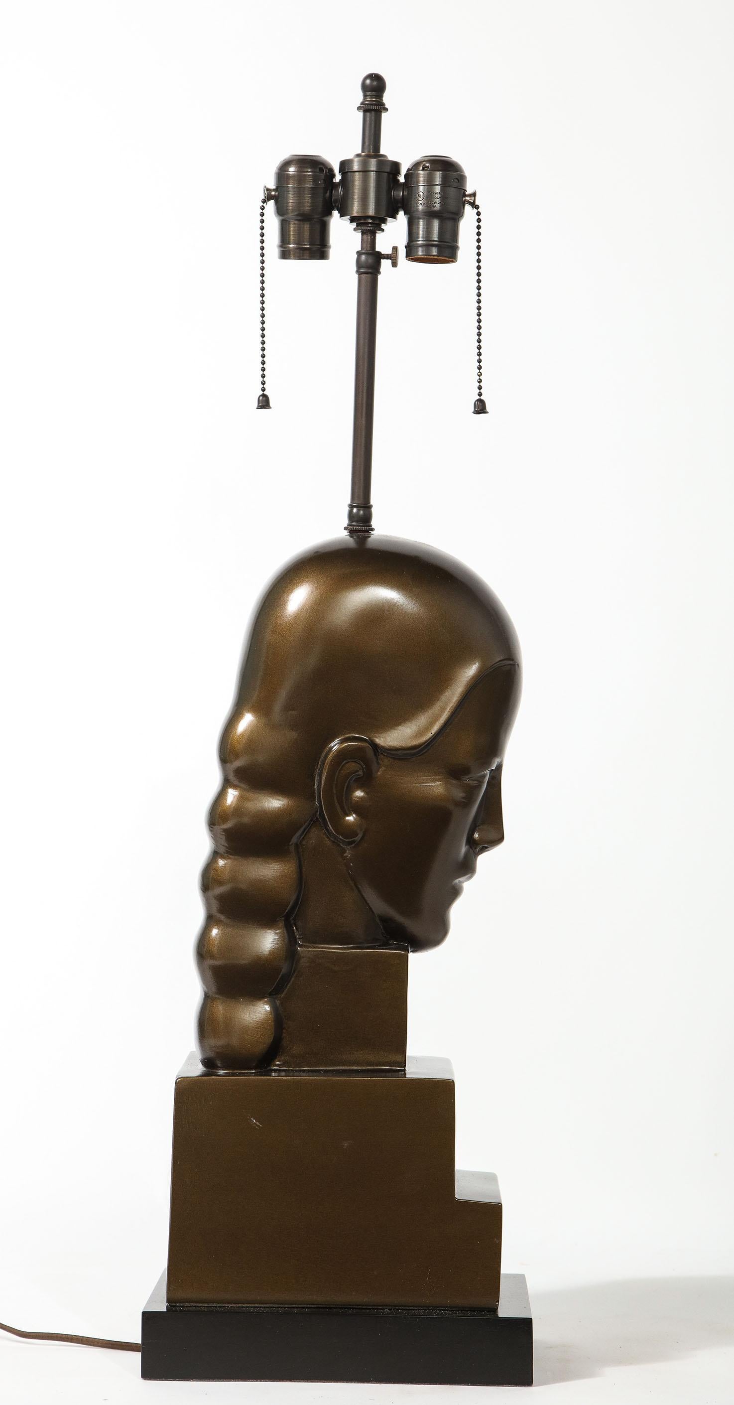 Le buste en bronze patiné d'une femme modelée dans un style Art déco sur un socle à gradins. Récemment câblé.