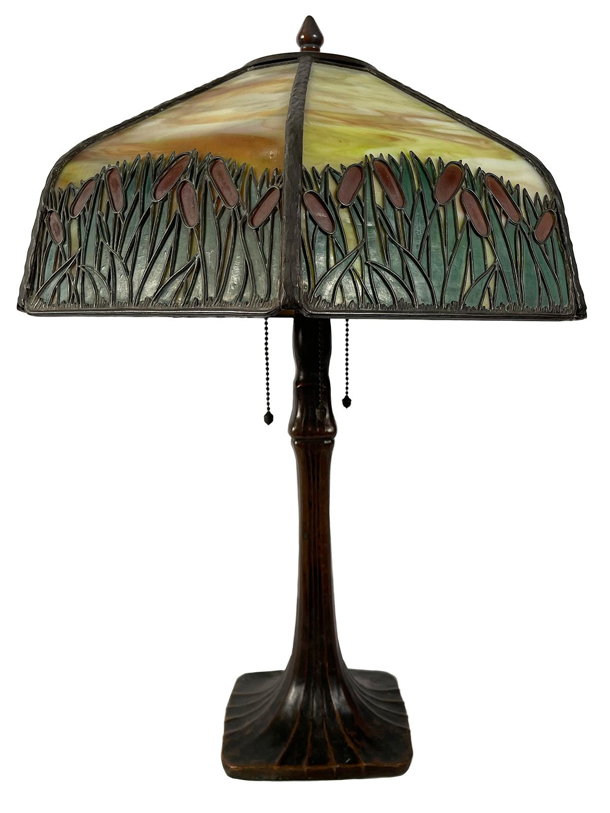 An early 20th century bronze lamp with slag glass and cattail motif. 

Dimensions: 23