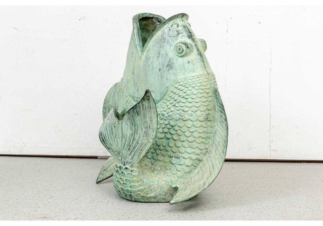 A classic Leaping Koi garden sculpture with wide open mouth and curled tail for support, hollow inside. In a weathered and desirable verdigris finish. 
Measures: H.26.5”, D. 15” W. 23.5”. 
Condition: there are expected stains inside and some