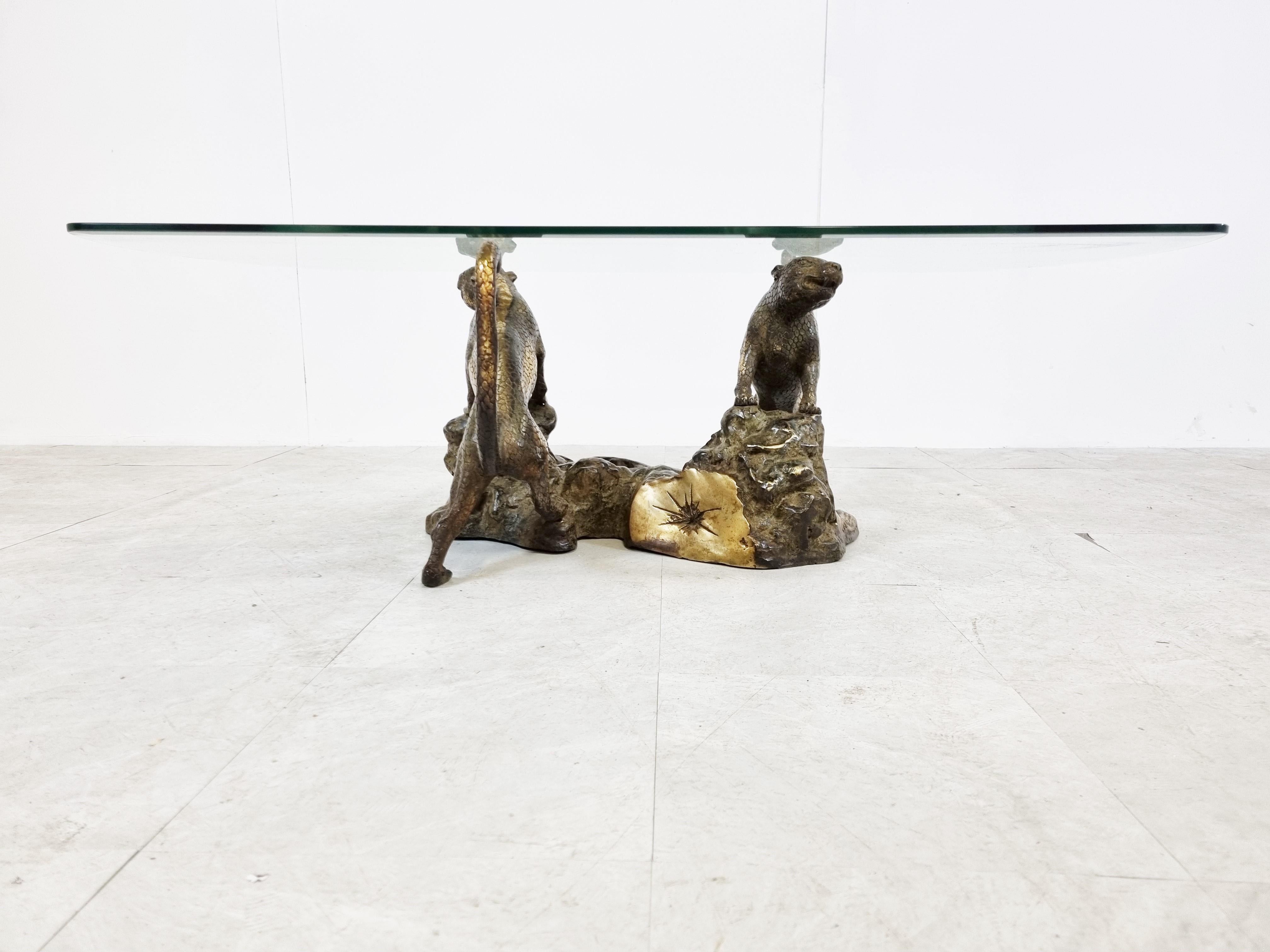 Spectacular coffee table depicting two proudly standing leopards on a rock.

The beautifully detailed base supports a clear glass beveled top.

The sculpture is signed but we don't recognize the signature.

1970s - France

Very good