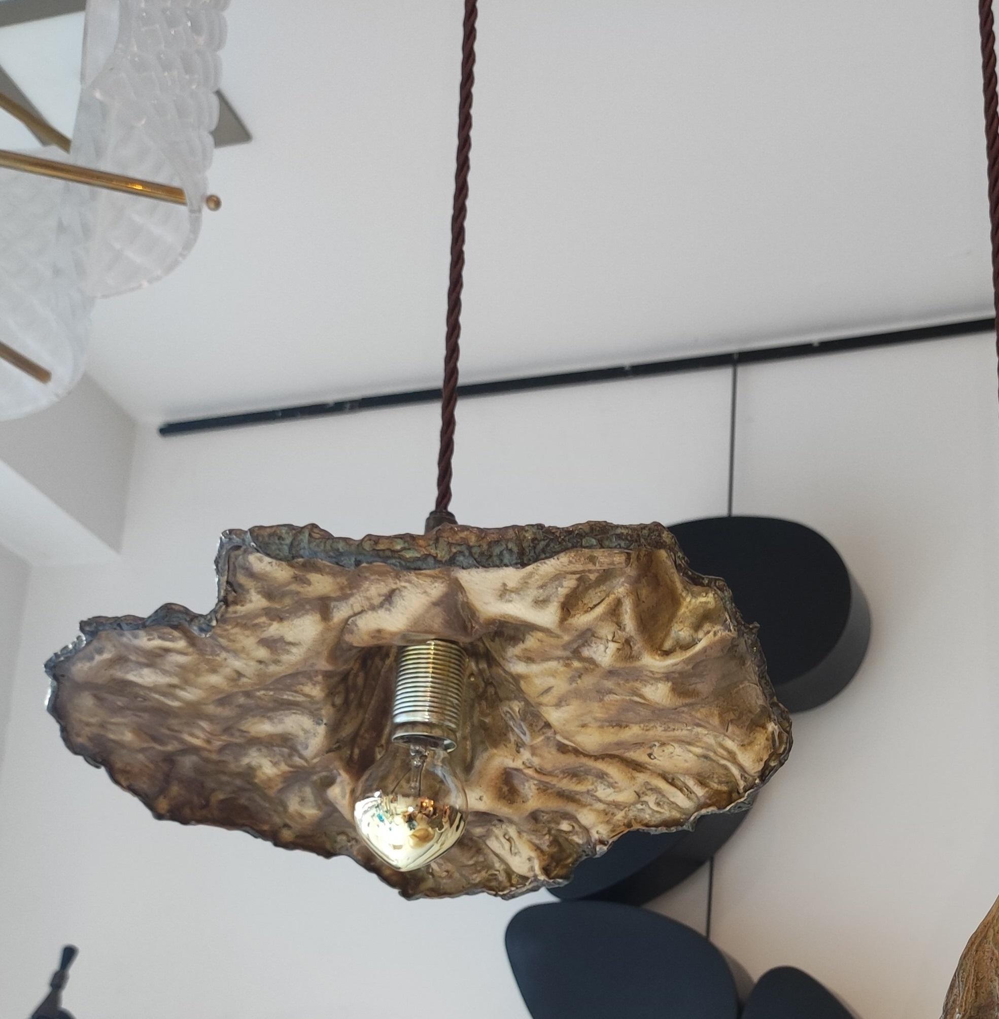 One bronze light suspension in the shape of a faded leaf, provided with a golden bulb. Golden interior.
Dimension: H 10 x 30 x 26 cm without the cord.
Max H: 160 cm (can be shortened).