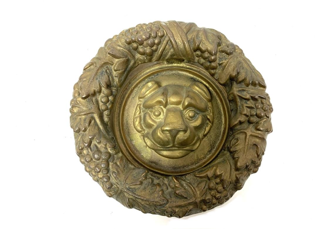 Battente rotondo in bronzo con cerniera, di buon peso e con una testa di leone in rilievo circondata da una corona di uva e foglie. Quattro fori per il montaggio sulla piastra posteriore. Non sono incluse viti. Non segnato.

Dimensioni: 6 1/2