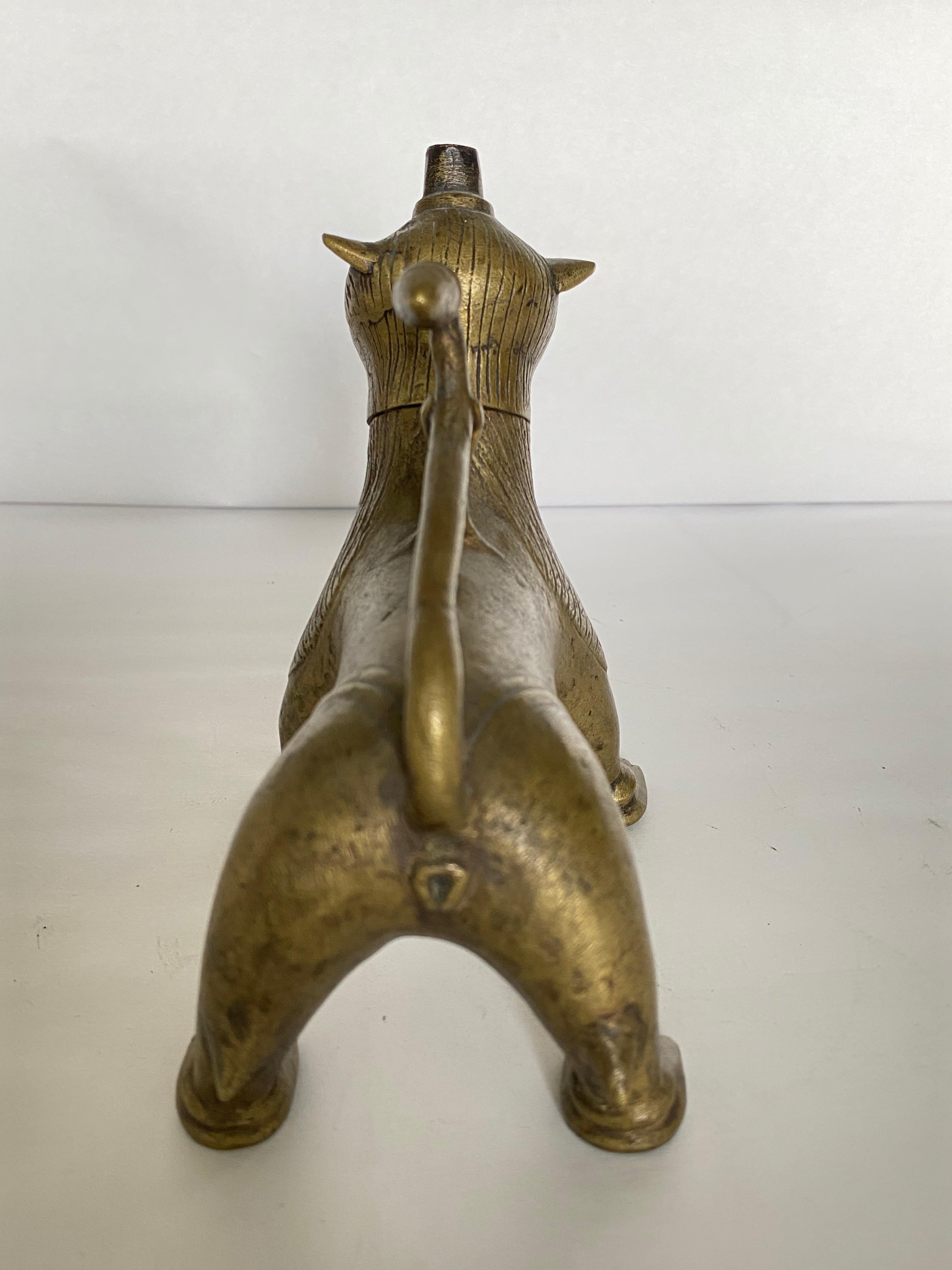 Indian bronze oil lamp in the form of the lion Vahana of the Goddess Durga. The head screws off for filling with oil. There is a hole at the top of the head for fitting a wick. The tail forms a handle for carrying the lamp.