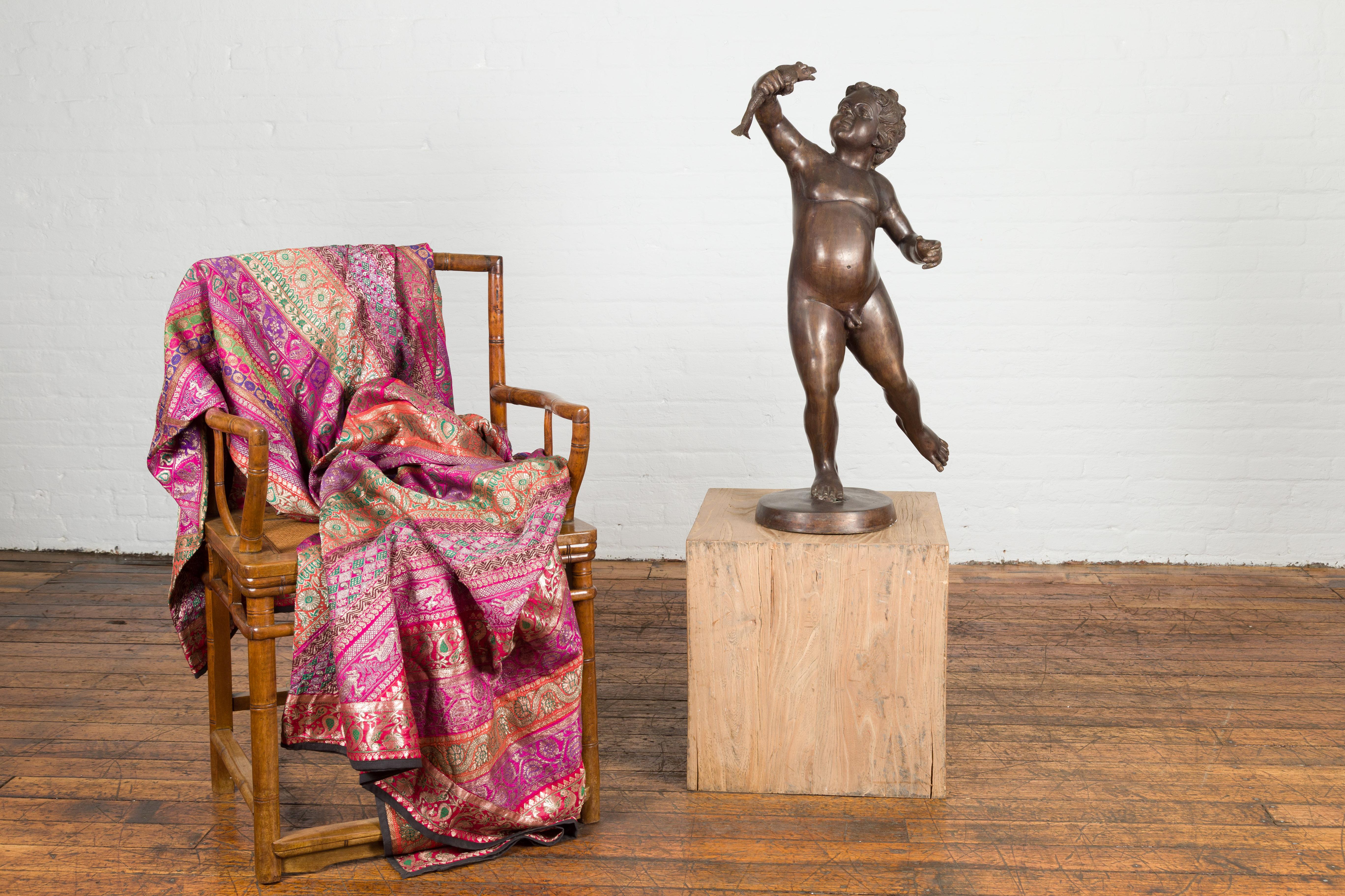 A lost-wax bronze tabletop statue of a putto poised on one foot holding a frog up in the air. This classic bronze tabletop sculpture is mounted on a modern round custom base, making it the perfect addition to office tables, coffee tables,