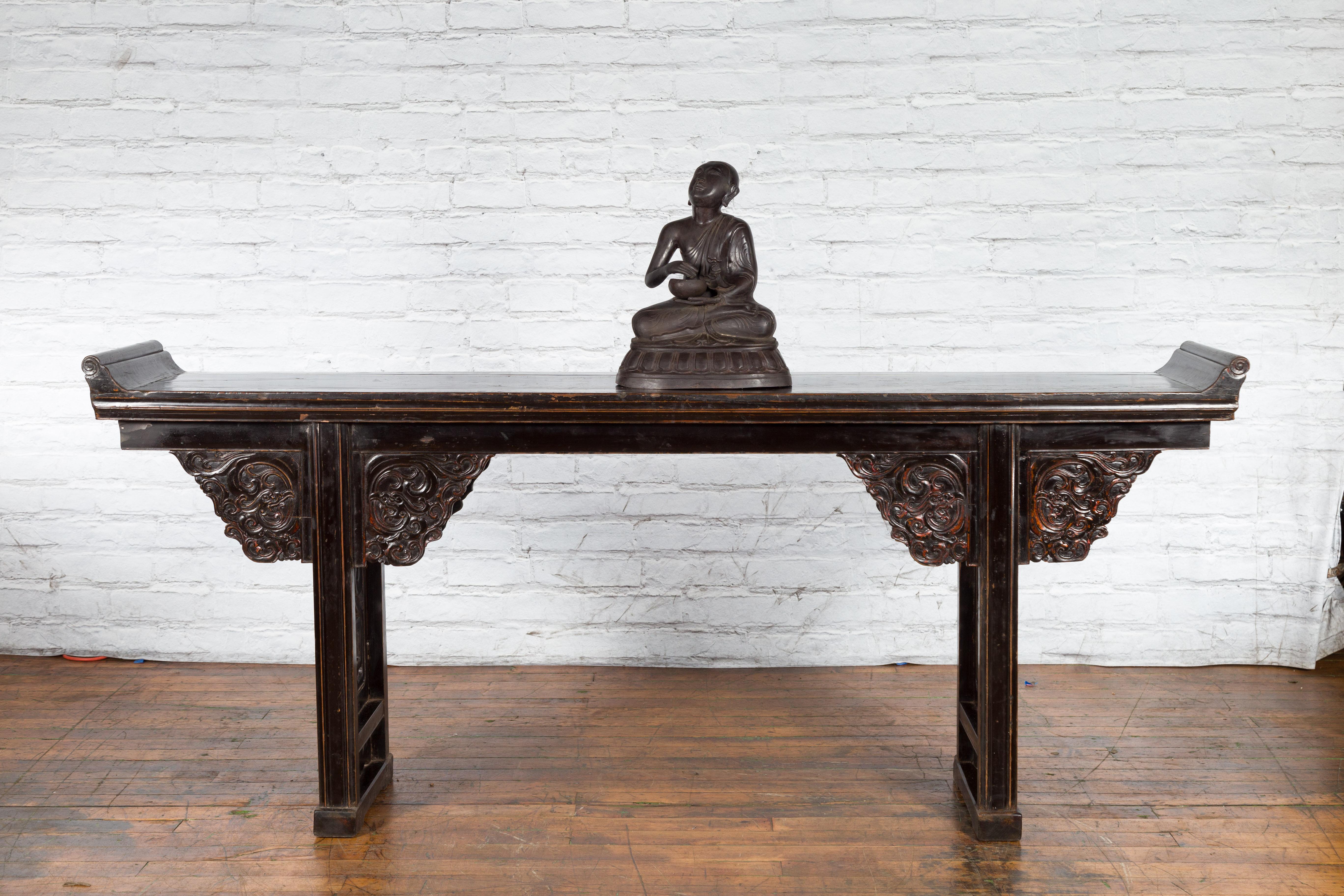 A small vintage bronze cast sculpture from the mid 20th century depicting a praying Buddhist monk sitting on a base and holding an offering bowl. Created with the traditional technique of the lost-wax (à la cire perdue) which allows for great