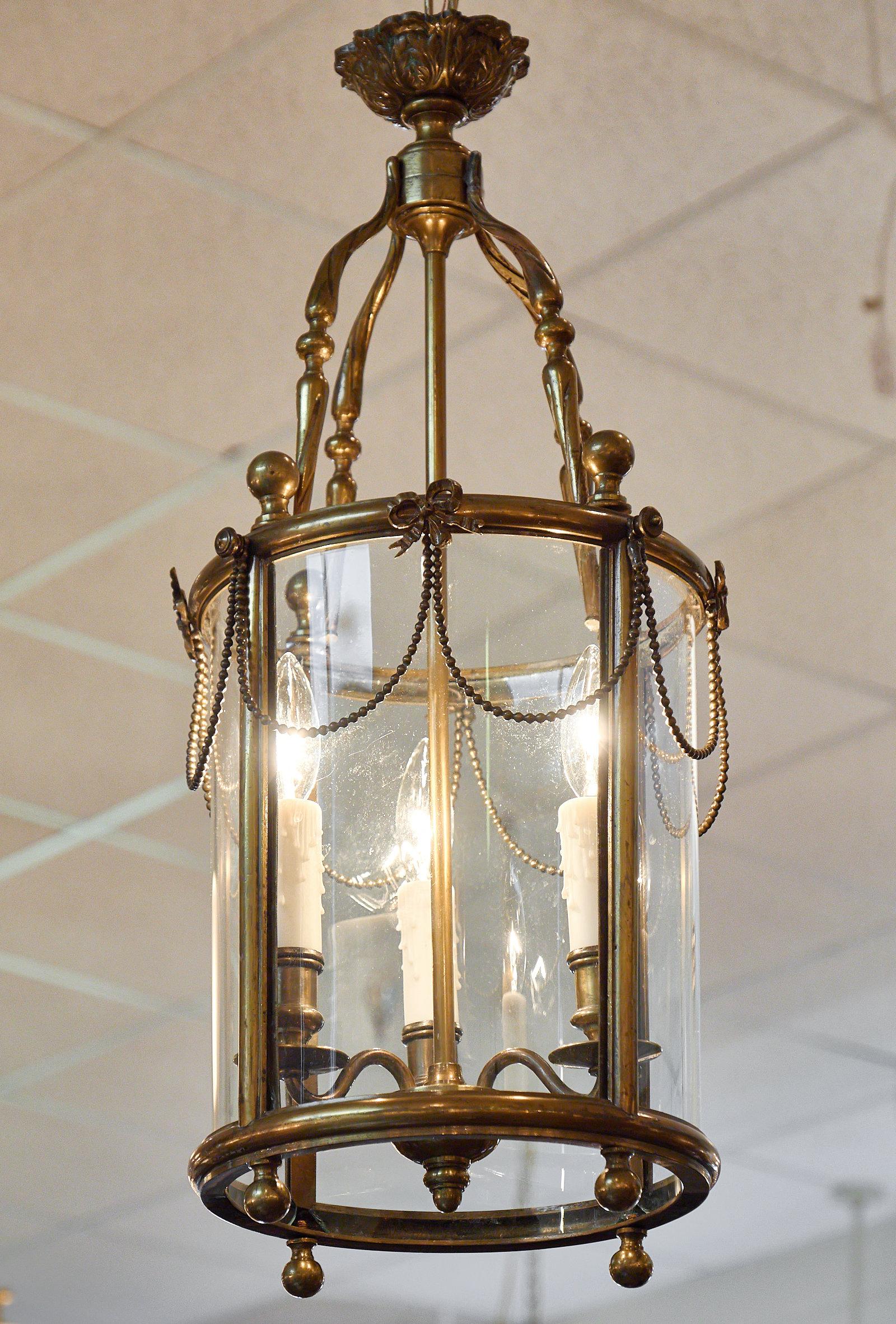 Louis XVI style bronze lantern. This fixture is made of finely cast bronze and features the original curved glass. We love the intricate detail to the structure. This lantern has been newly wired to fit US standards.